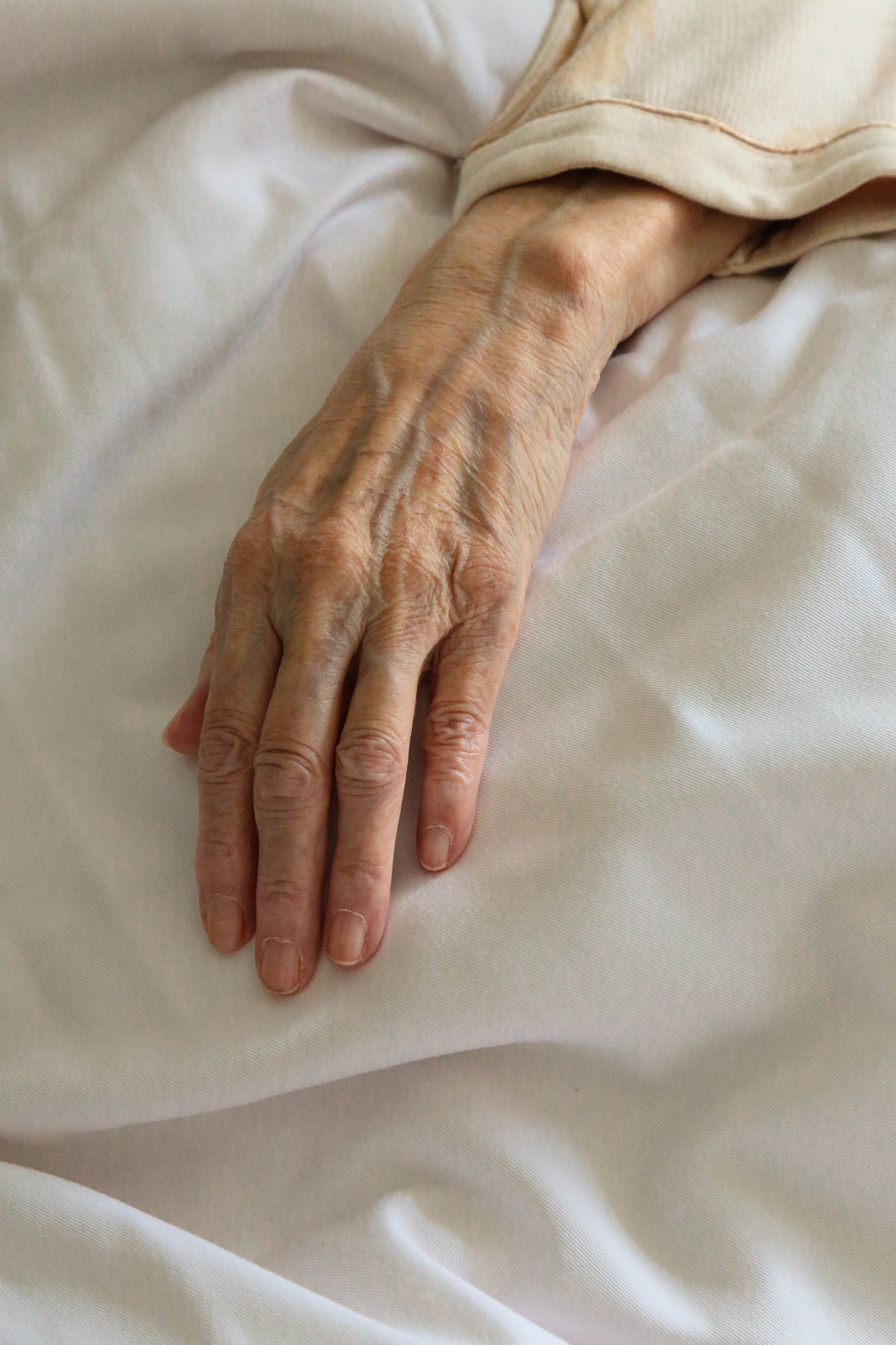 Une main ridée reposant sur un drap | photo : Freepik