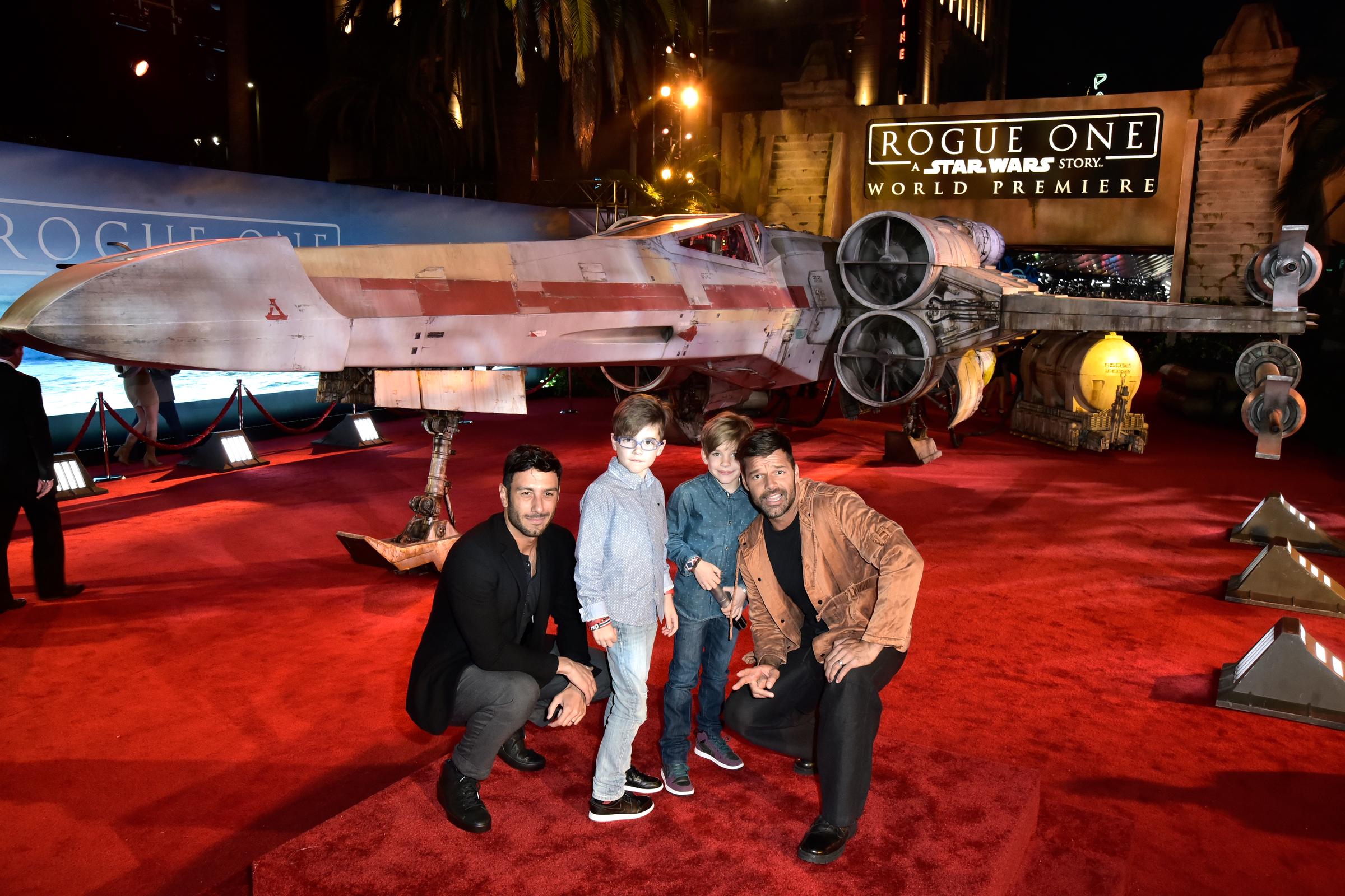Ricky Martin and Jwan Yosef crouch beside Matteo Martin and Valentino Martin on the red carpet at the "Rogue One: A Star Wars Story" world premiere in Hollywood.