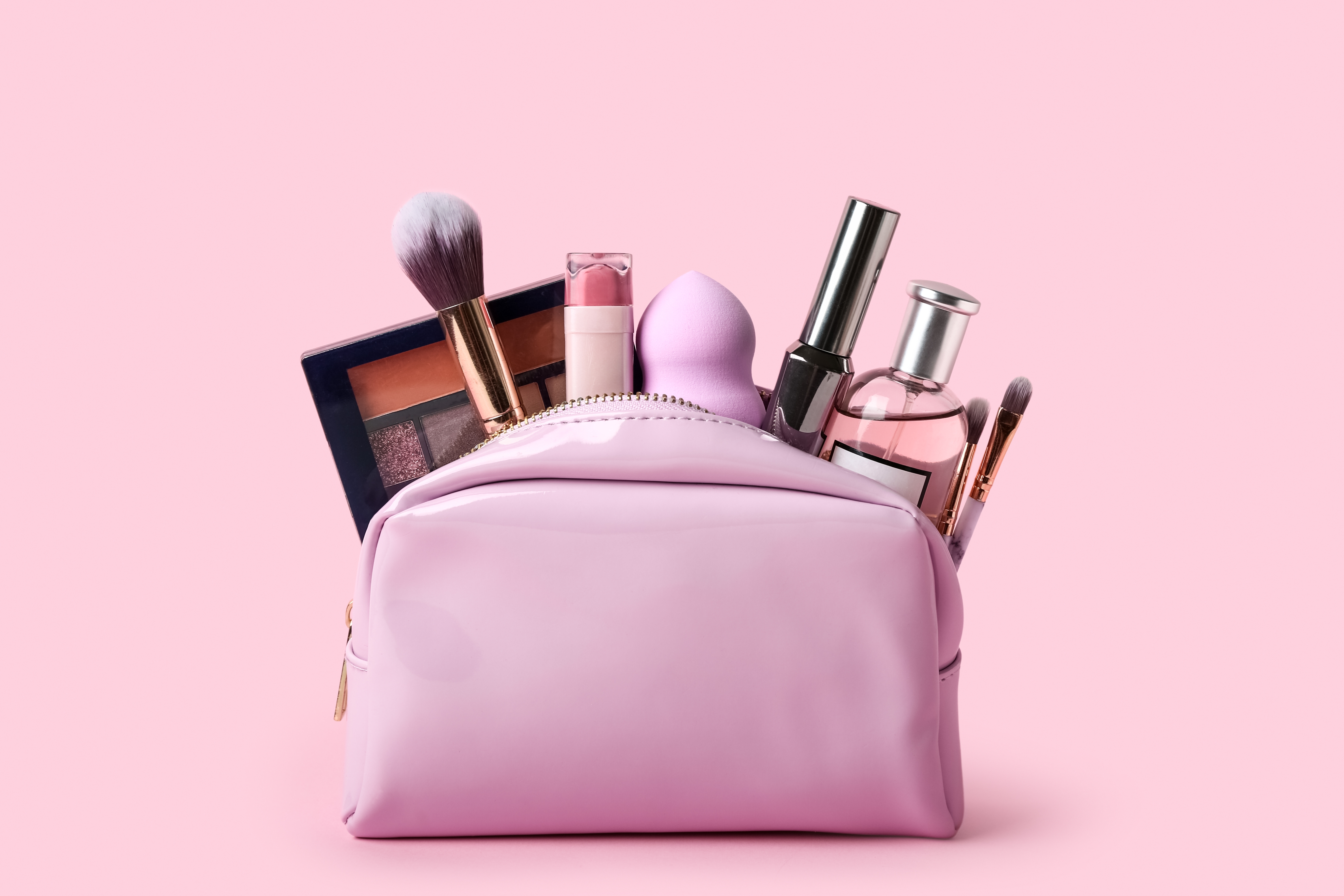 A pink makeup bag filled with beauty products | Source: Shutterstock