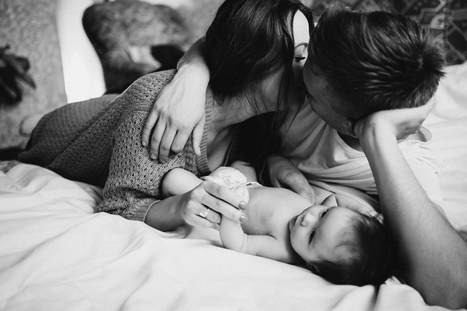 Couple with their newborn baby on bed | Source: Pexels