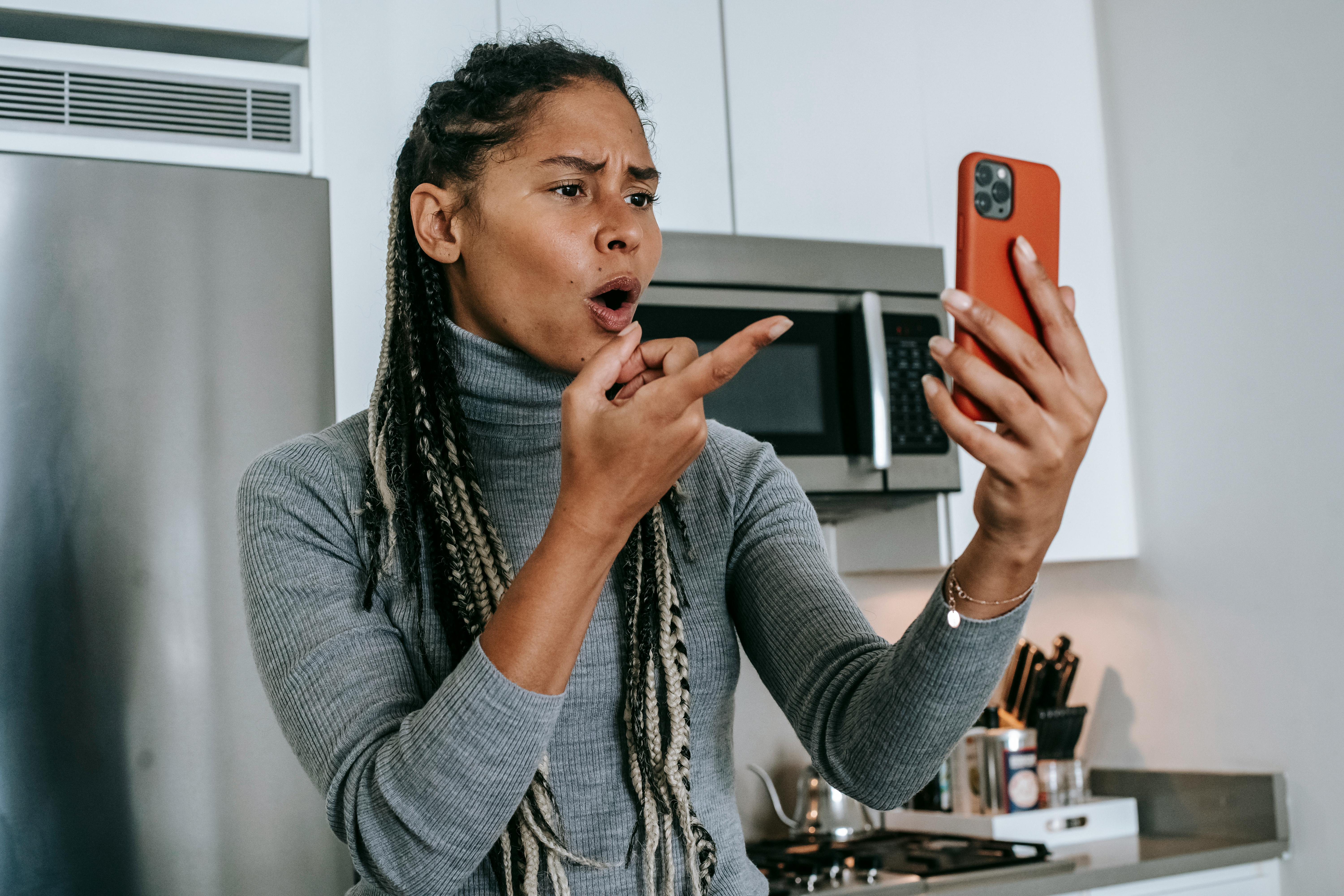 An upset woman gesturing with her hand to her phone | Source: Pexels