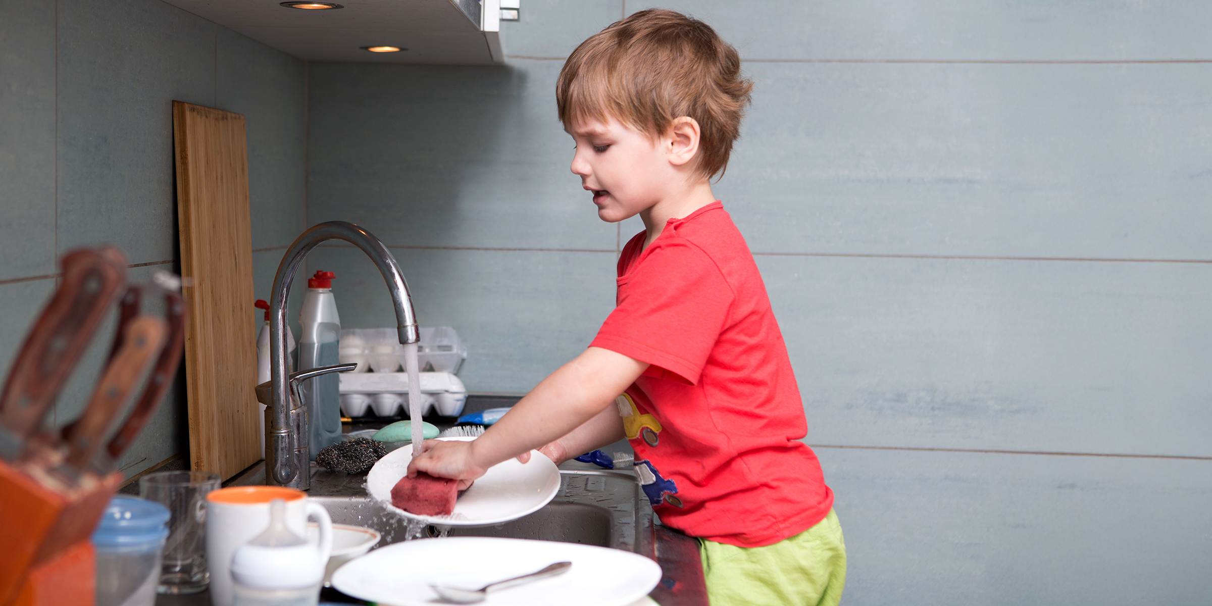 A boy washing dishes | Source: Shutterstock