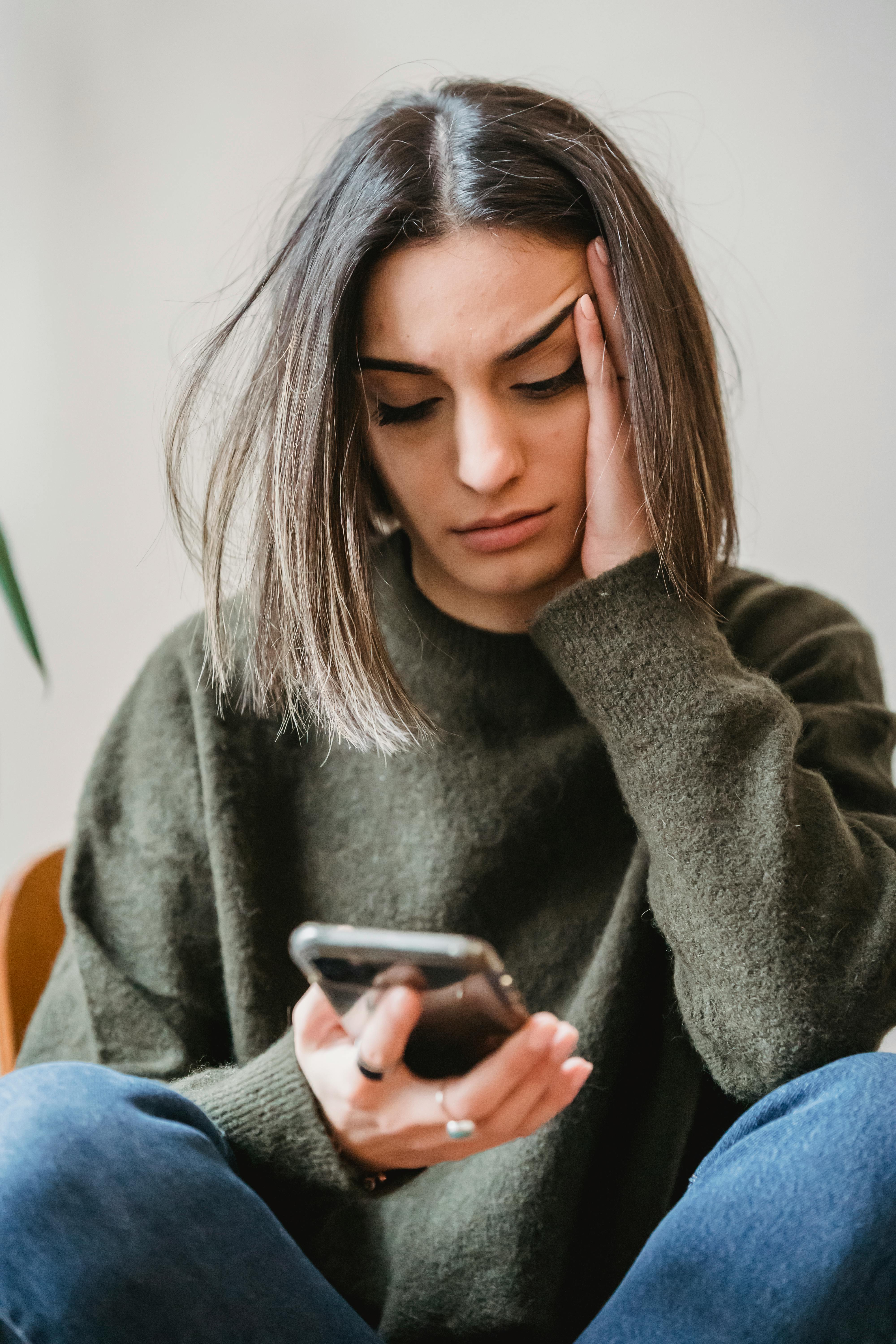 A woman looking unhappy while looking at her phone | Source: Pexels