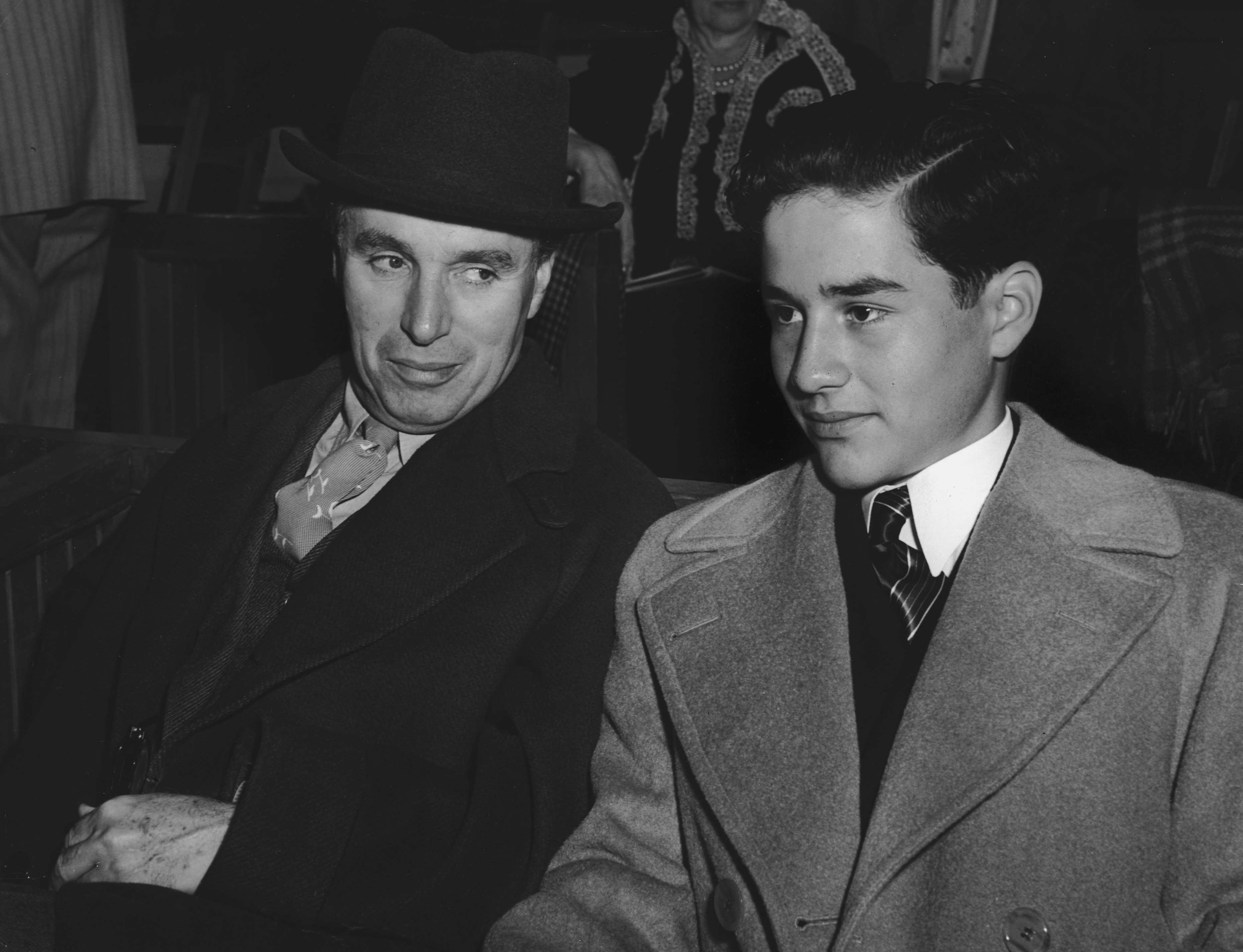 Charlie Chaplin seated in a stadium next to his son, Charles Jr., circa 1940 | Source: Getty Images