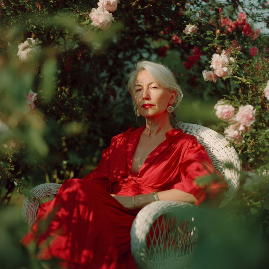 A woman in a red dress sitting in a garden chair | Source: Midjourney