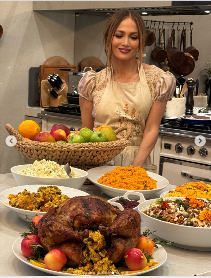 Jennifer Lopez wears a smile as she photographs with the table filled with the holiday meals, as seen from a post dated November 28, 2025. | Source: Instagram/jlo