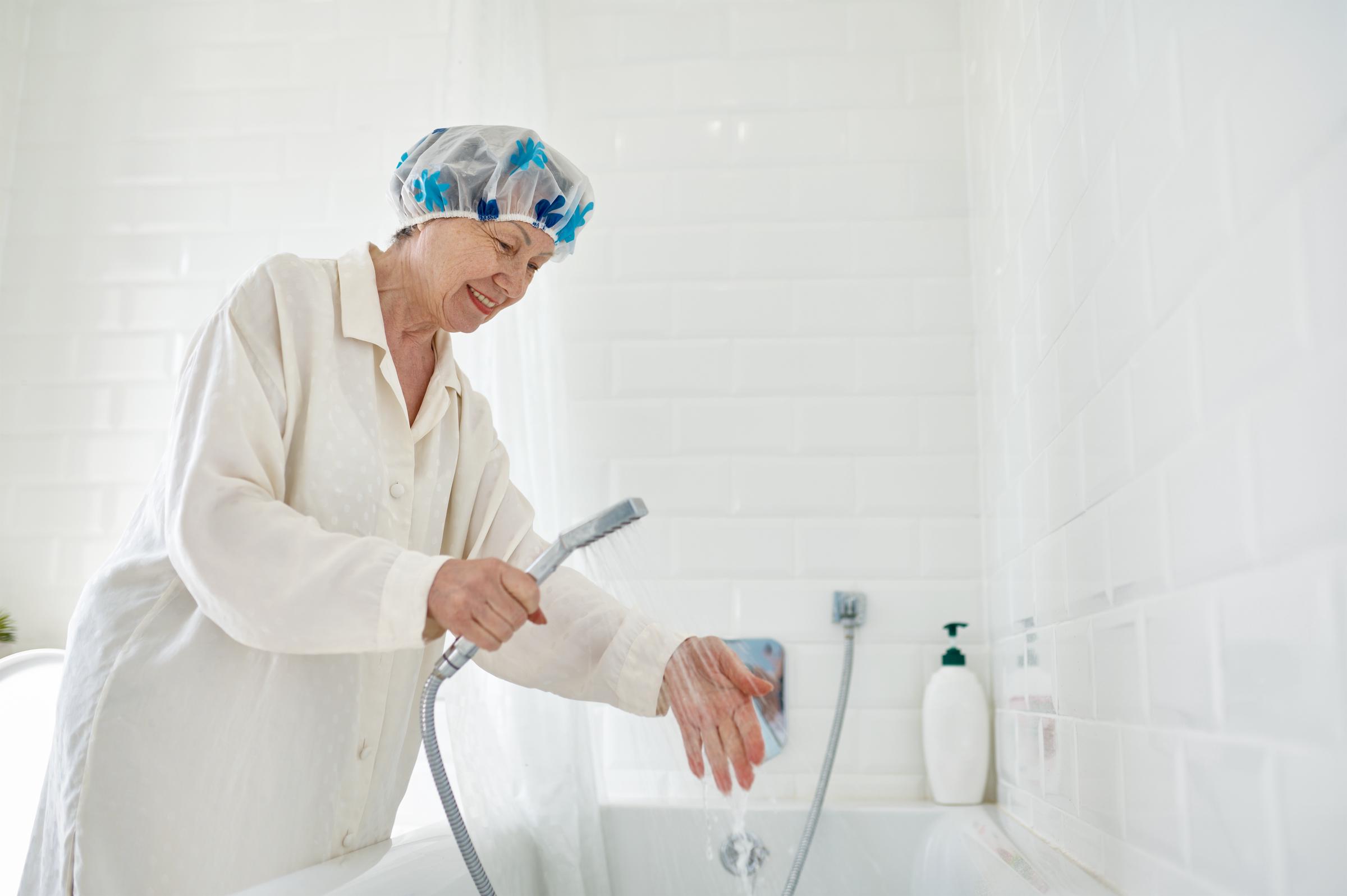 Woman checking the water temperature before taking a shower | Source: Shutterstock