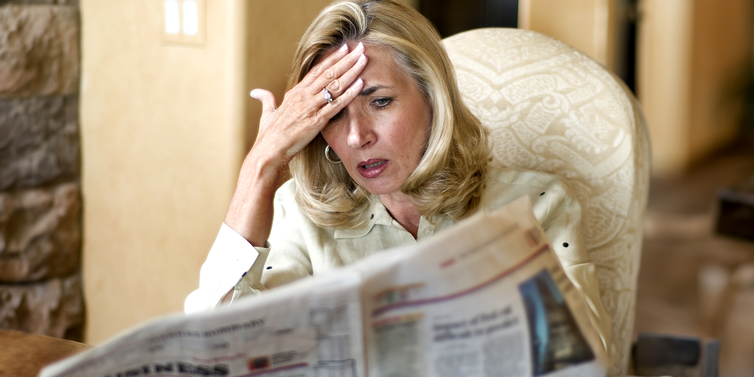 A shocked woman reading a newspaper | Source: Shutterstock