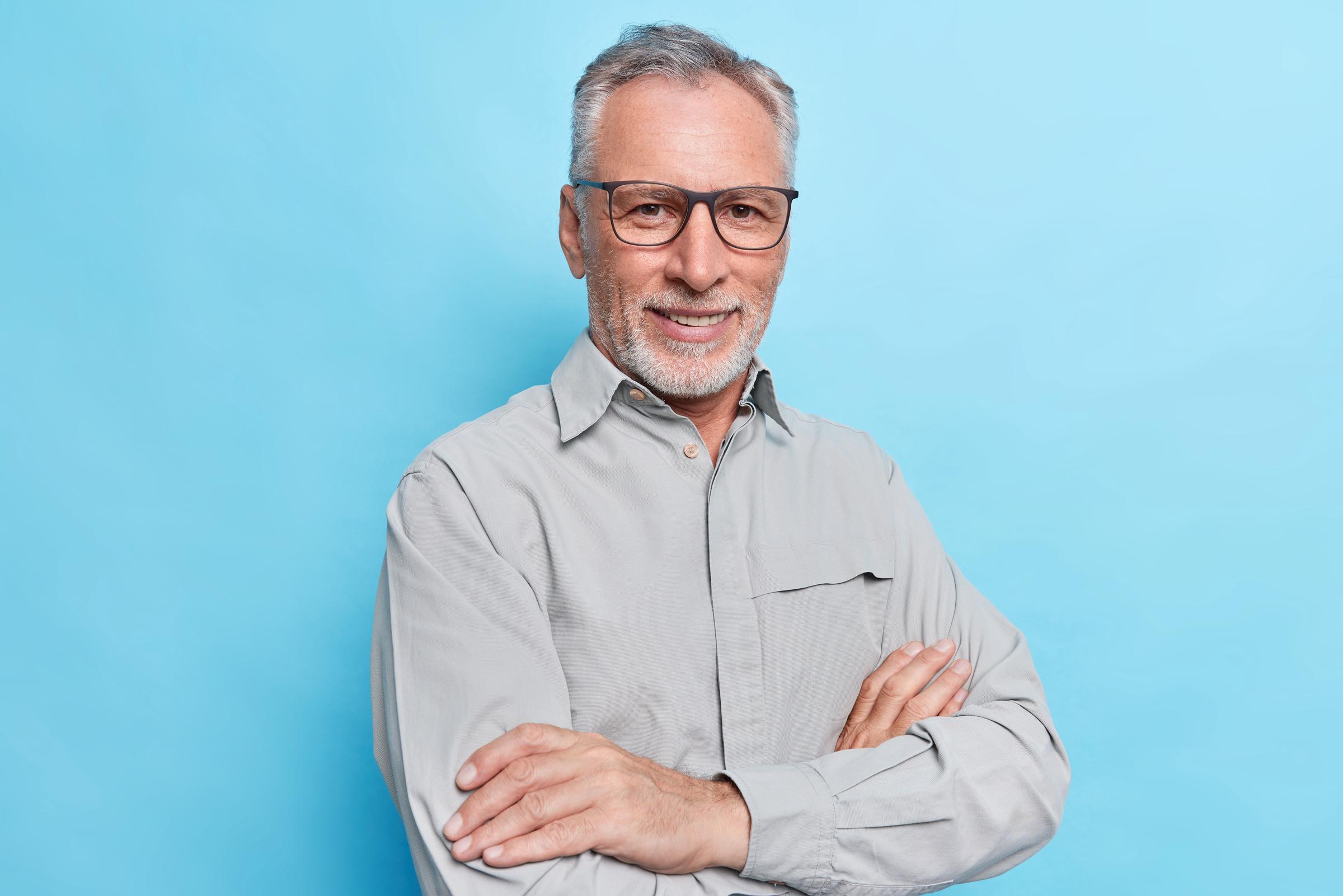 A smiling middle-aged man with his arms crossed | Source: Freepik