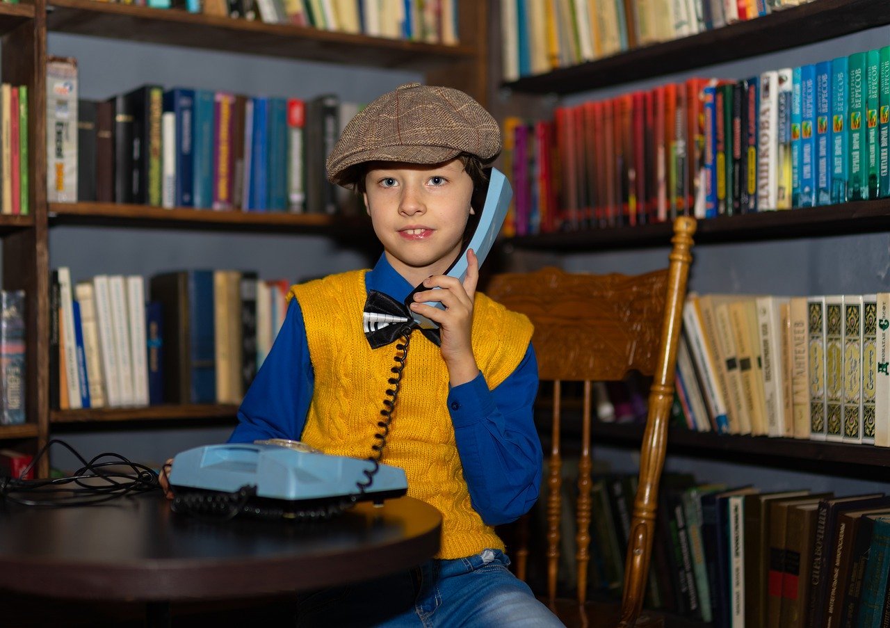 Niño hablando por un teléfono antiguo. | Foto: Pixabay