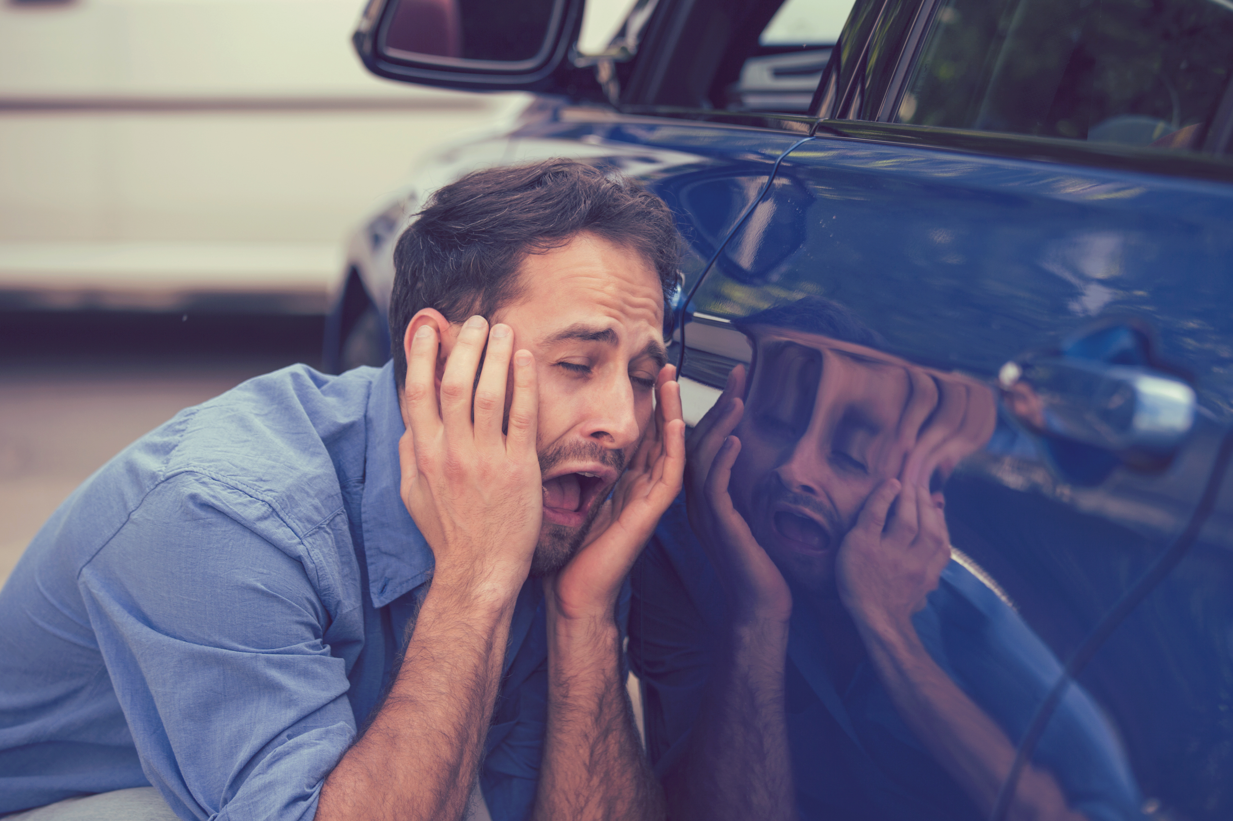 Frustrated upset young man looking at scratches and dents on his car outdoors | Source: Getty Images