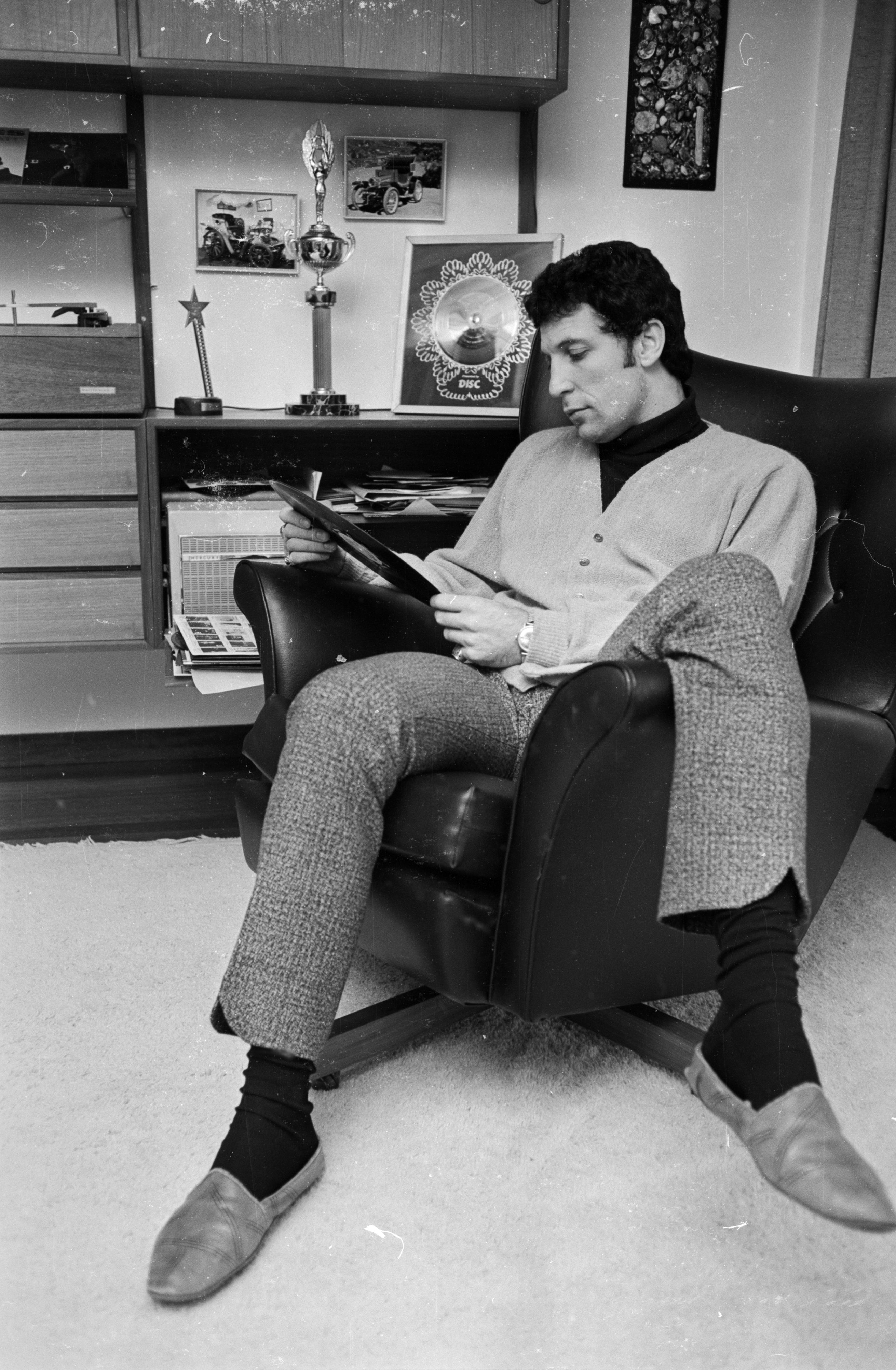 Tom Jones pictured seated while holding a record at home on April 20, 1966. / Source: Getty Images