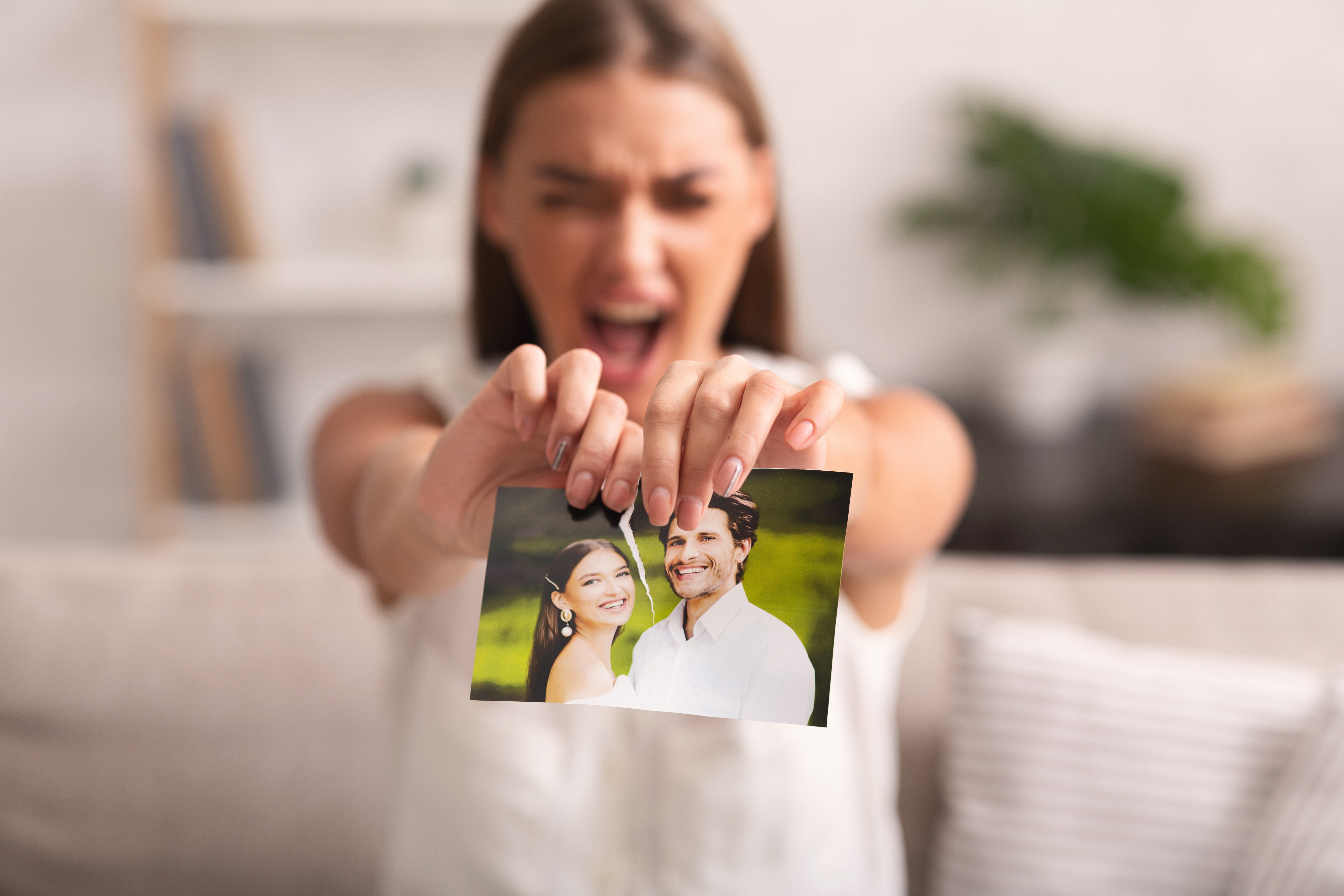 A woman tearing up a photo of her and a man | Source: Shutterstock