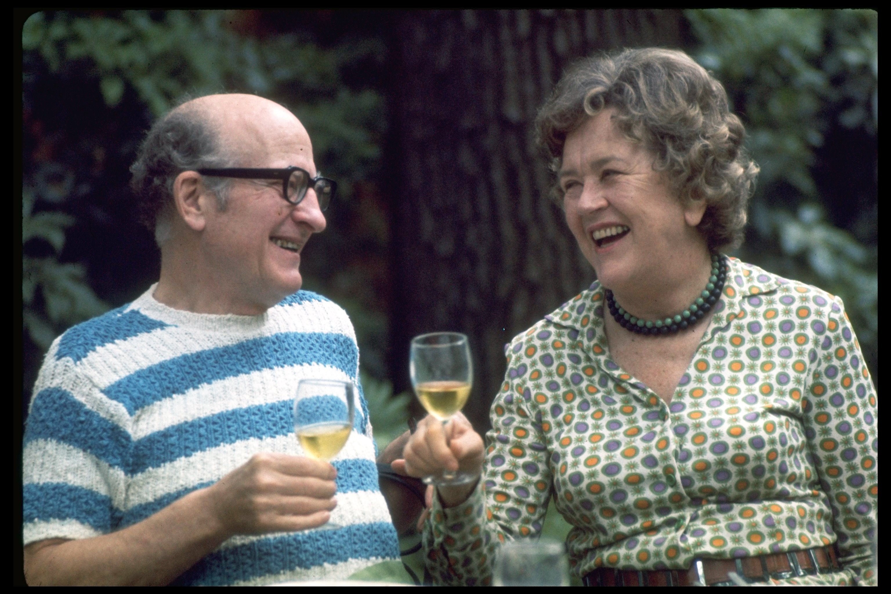 Julia Child and husband, Paul Child, enjoying a convivial glass of wine in outdoor setting. Photo: Getty Images