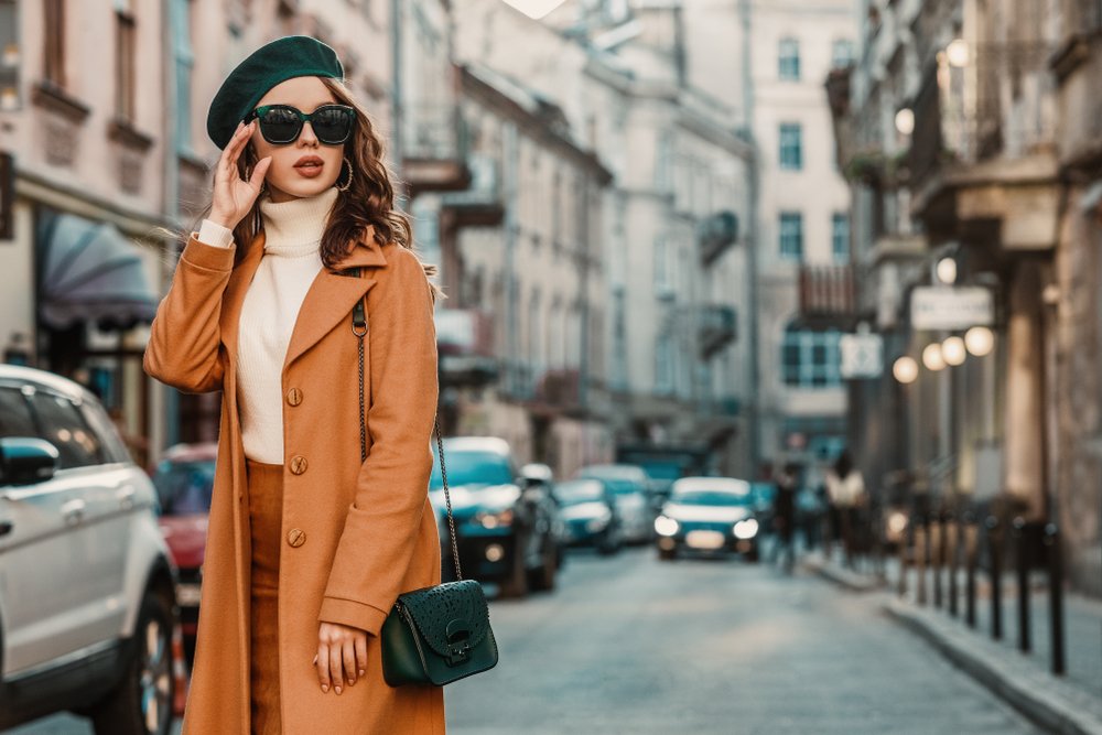 Mujer usando un abrigo de invierno color marrón, franela clara de cuello alto y gorro negro. | Foto: Shutterstock