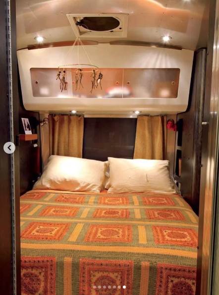 At the other end of the Airstream, McConaughey's snug bedroom turned the trailer's curved architecture into part of its appeal. He nicknamed the warm-toned sleeping space the Honeycomb, where a patterned bedspread, overhead storage, small reading lights, and curtains created a surprisingly intimate retreat inside the 28-foot home he carried across the road. | Source: Instagram/ivd_ru