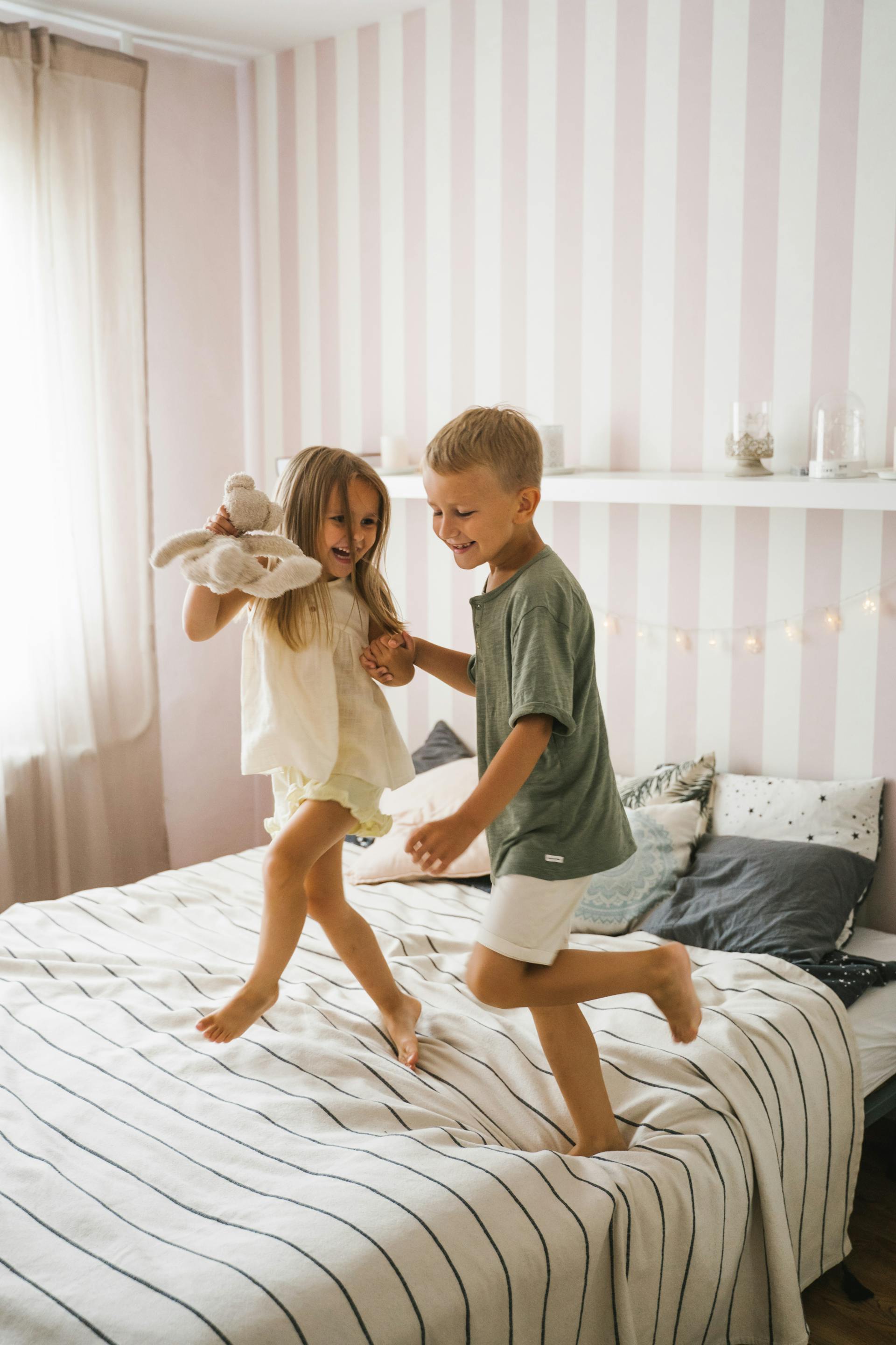 A happy boy and girl dancing on the bed | Source: Pexels
