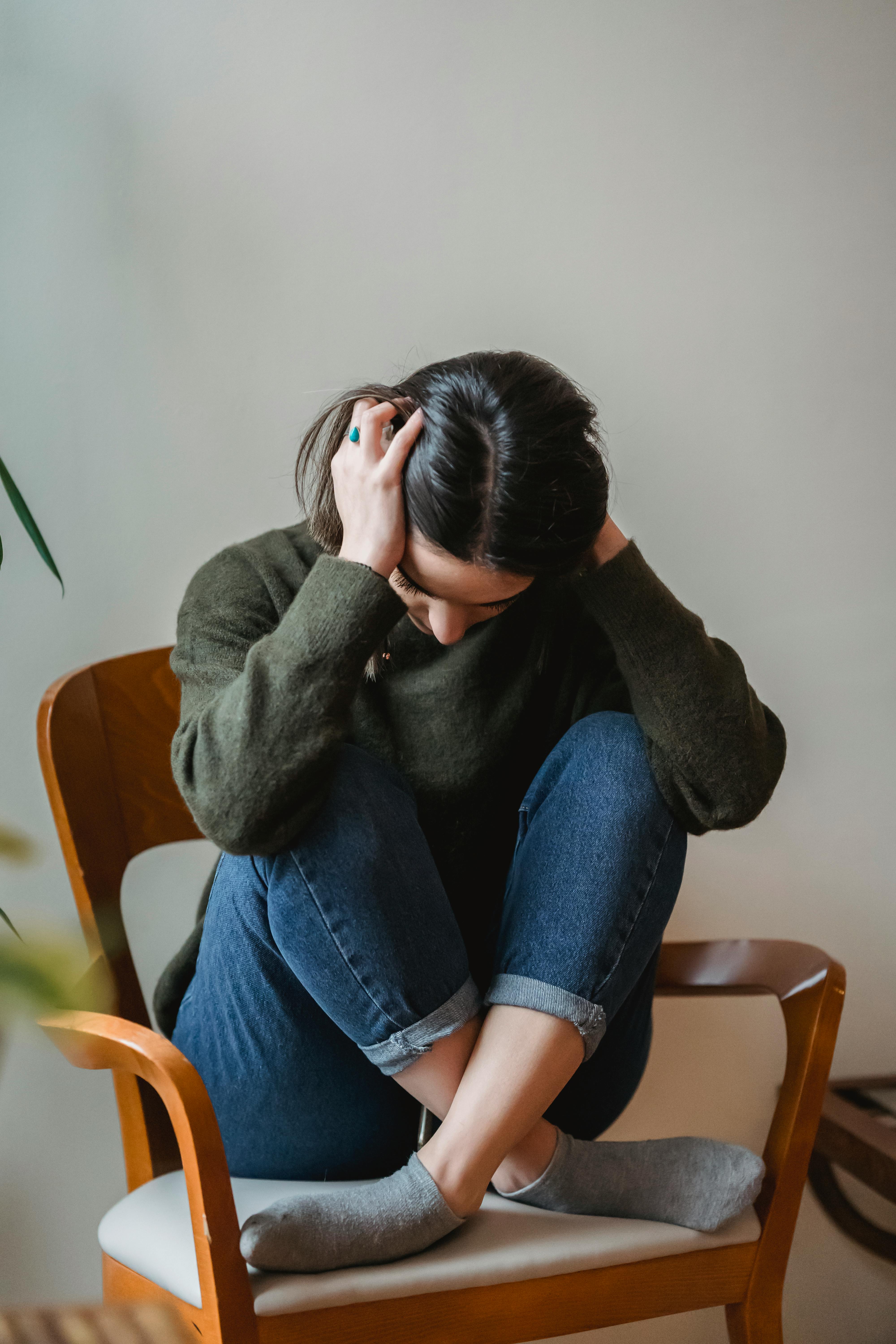 A woman sitting on a chair, holding her head in despair | Source: Pexels