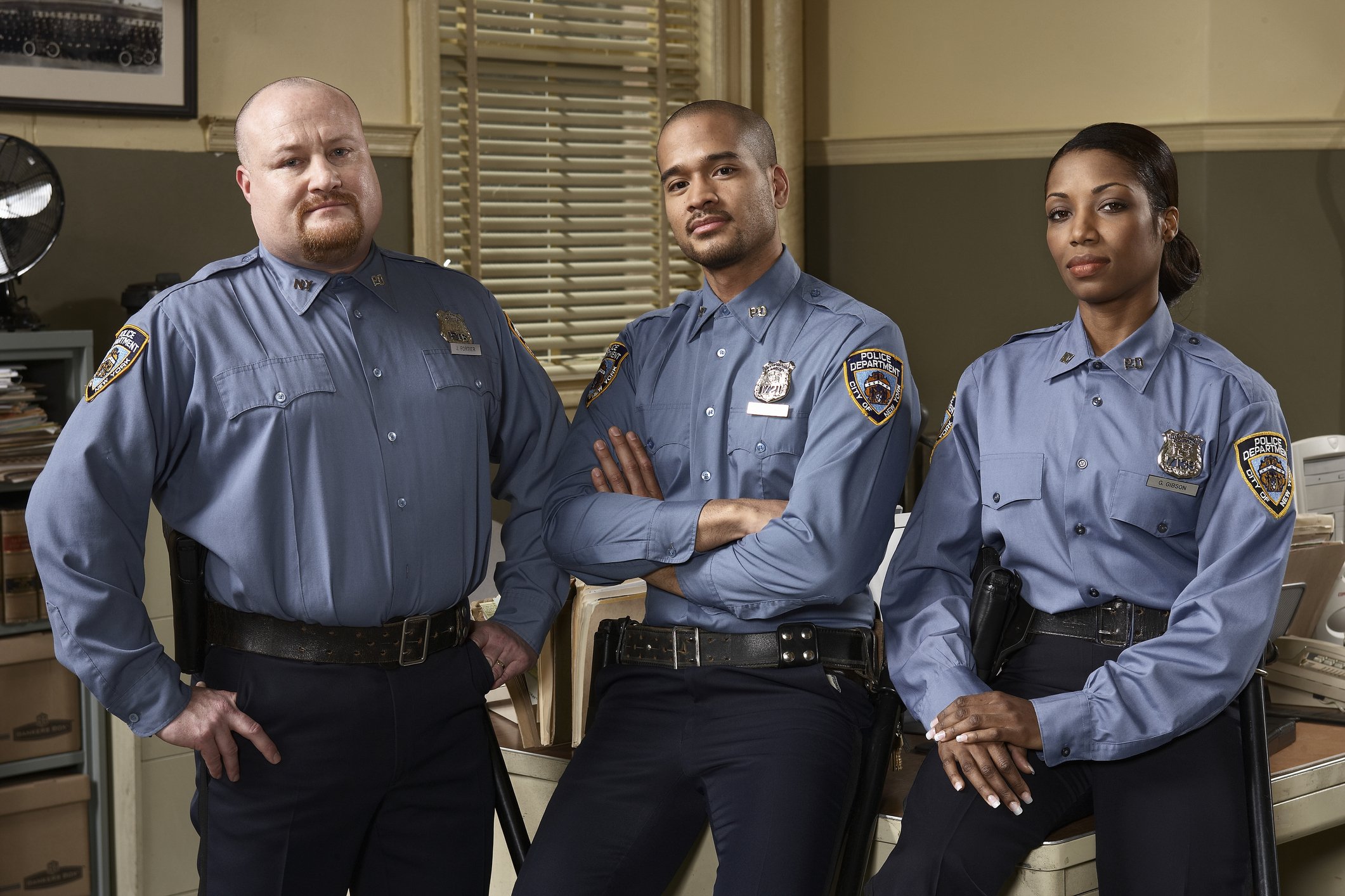 A potrait picture of three police officers at a police station. | Photo: Getty Images