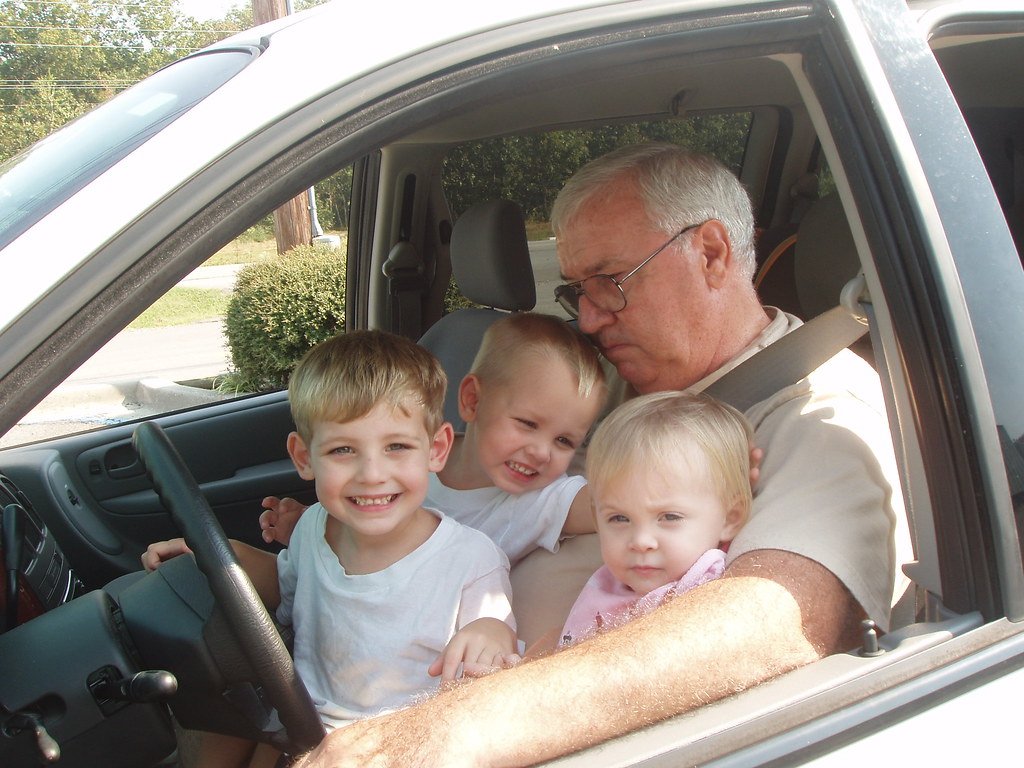A grandfather in a car with his three grandchildren