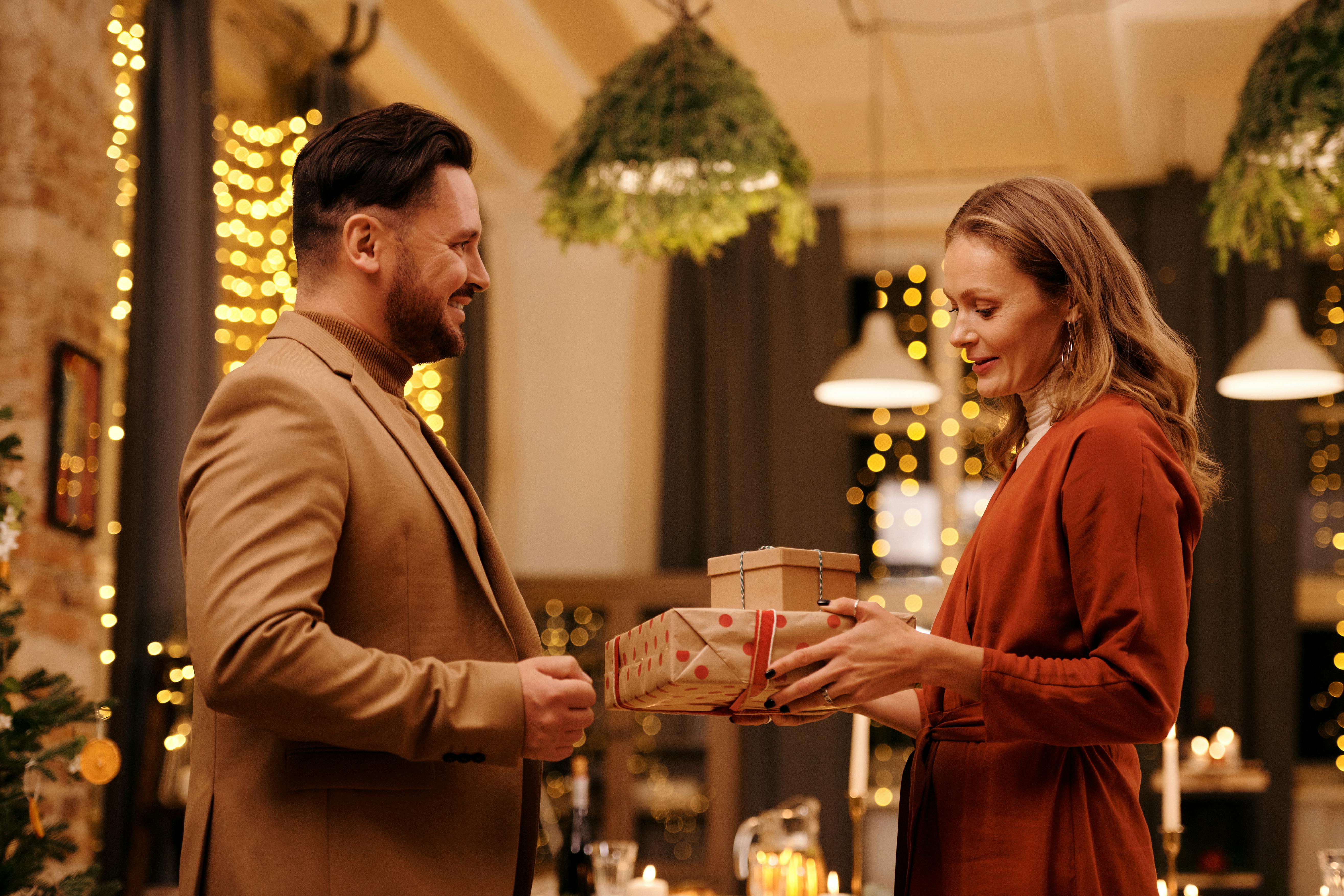 A woman holding gift boxes while standing in front of a man | Source: Pexels