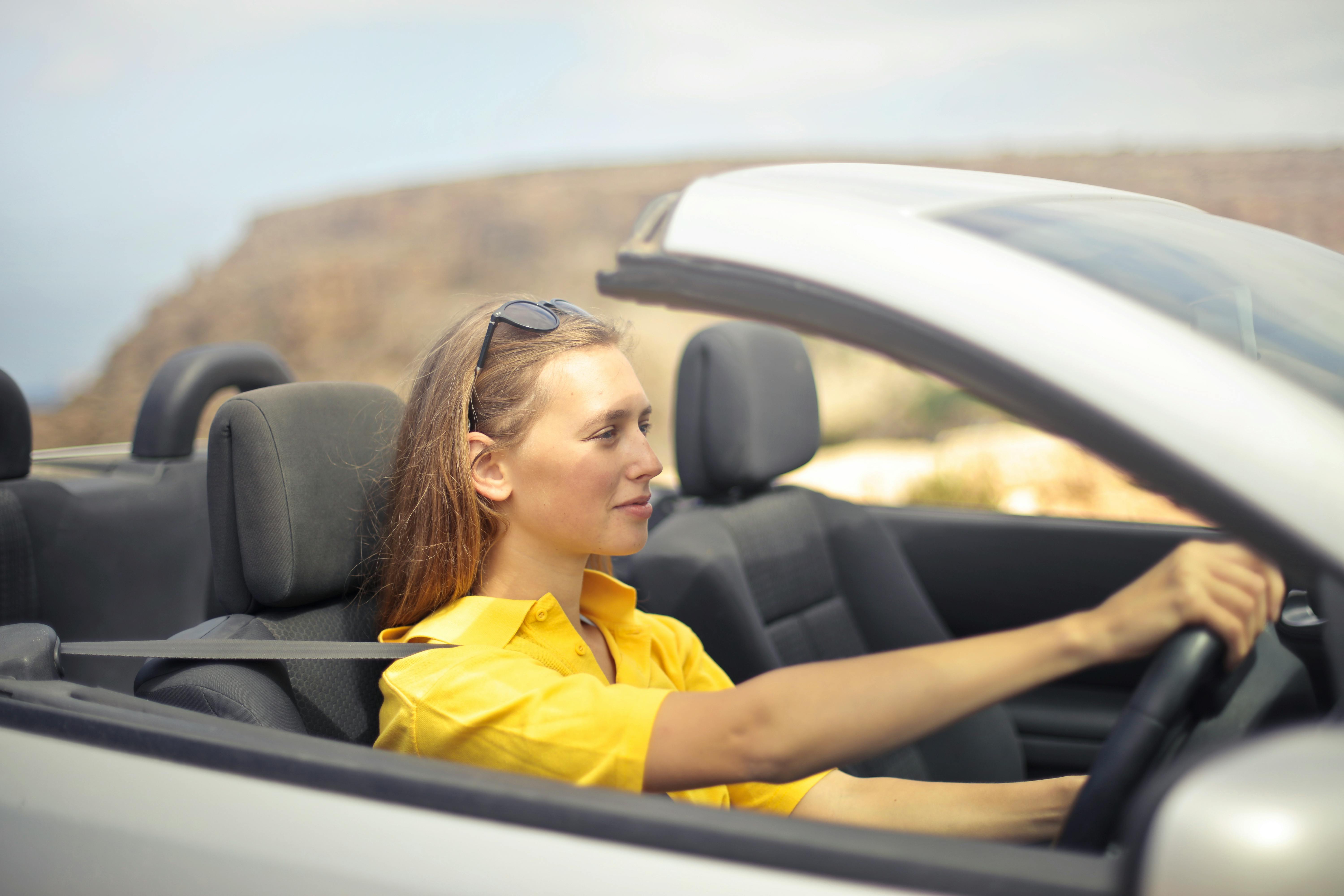 A woman in a yellow shirt driving | Source: Pexels