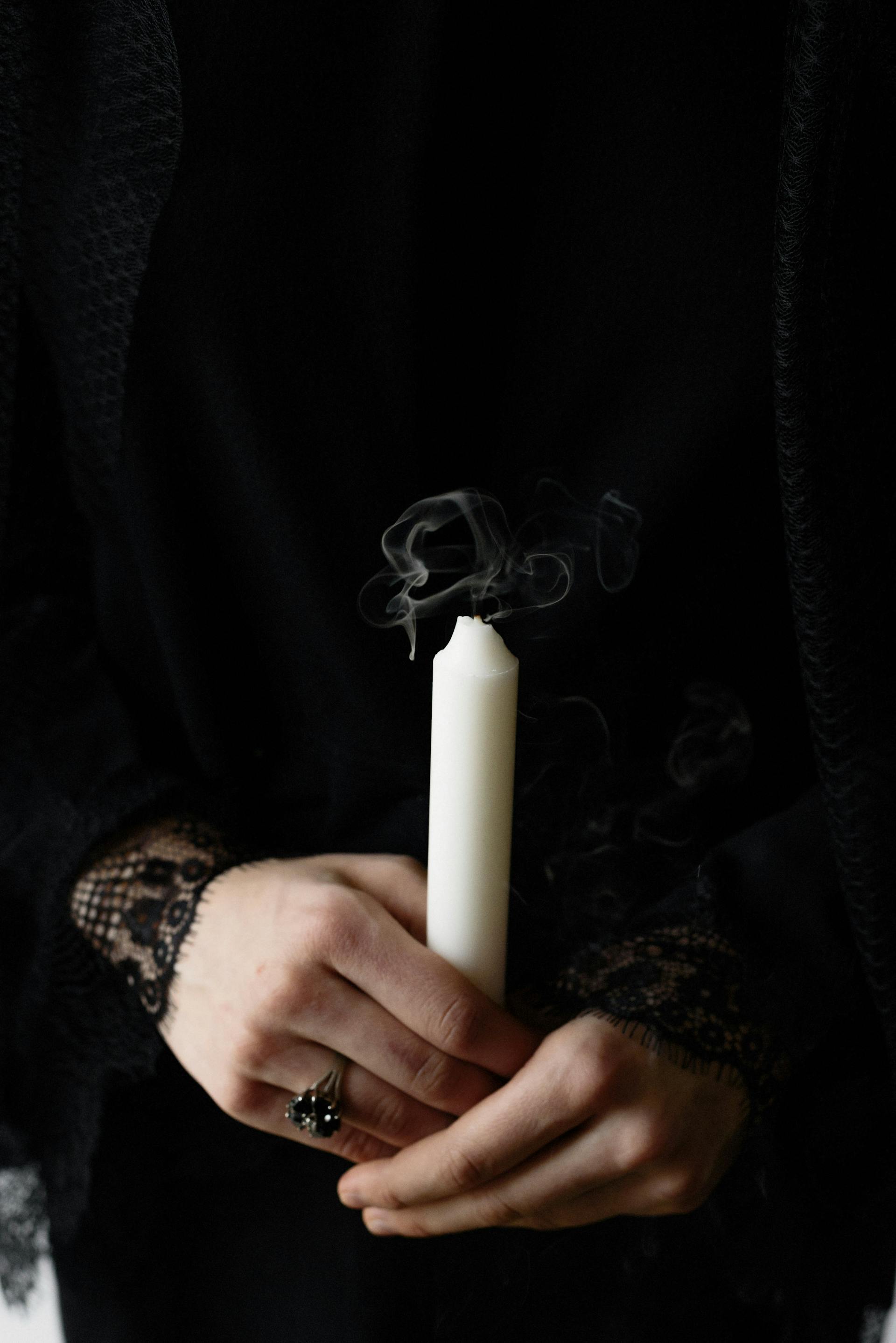 A woman in a black dress holding a white candle | Source: Pexels
