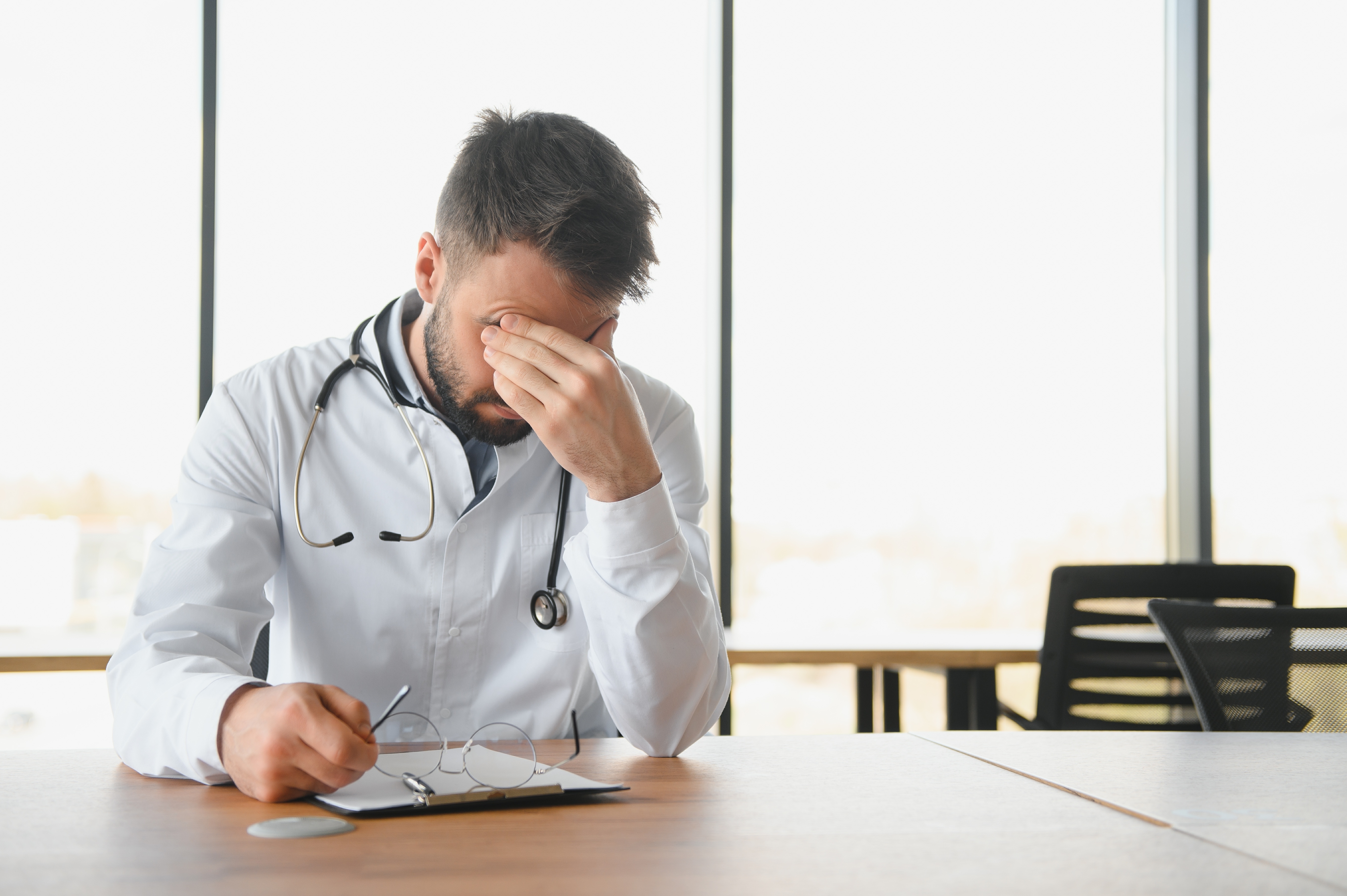 A young male doctor feeling exhausted | Source: Shutterstock