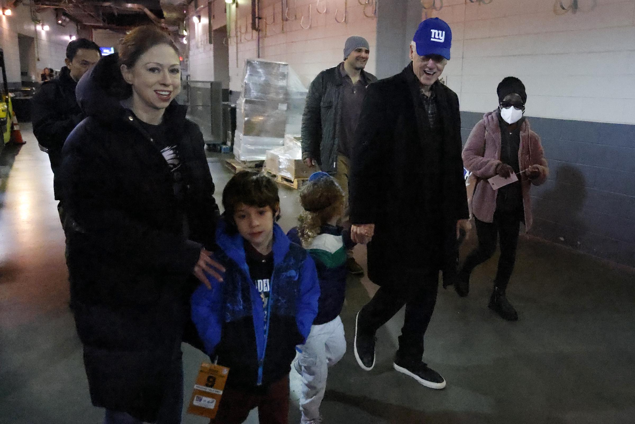 Bill Clinton walks with his daughter, Chelsea, and her children before the game between the Philadelphia Eagles and New York Giants at MetLife Stadium in New Jersey, on December 11, 2022 | Source: Getty Images