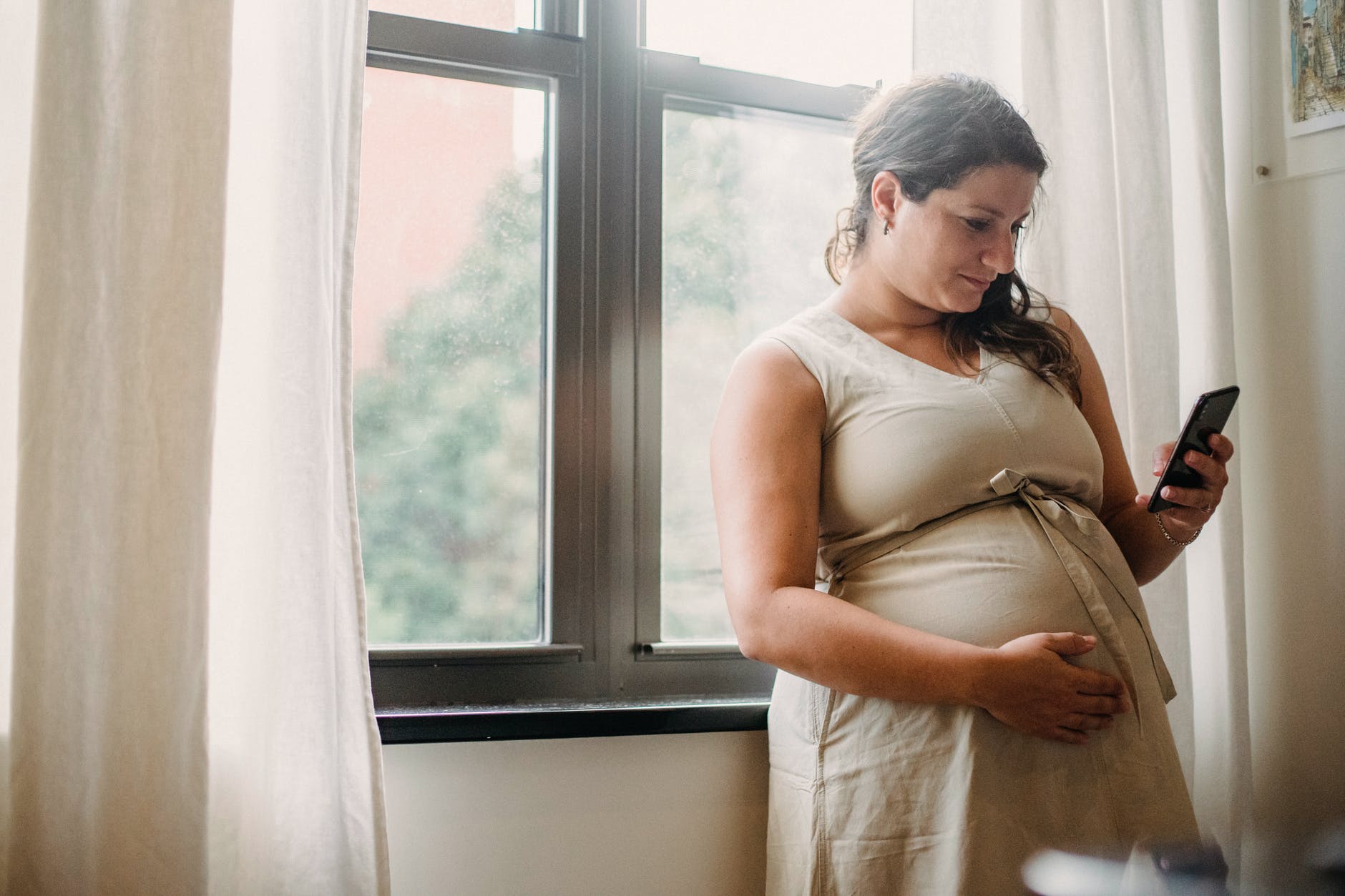 Mujer embarazada haciendo una llamada por un teléfono celular. | Foto: Pexels