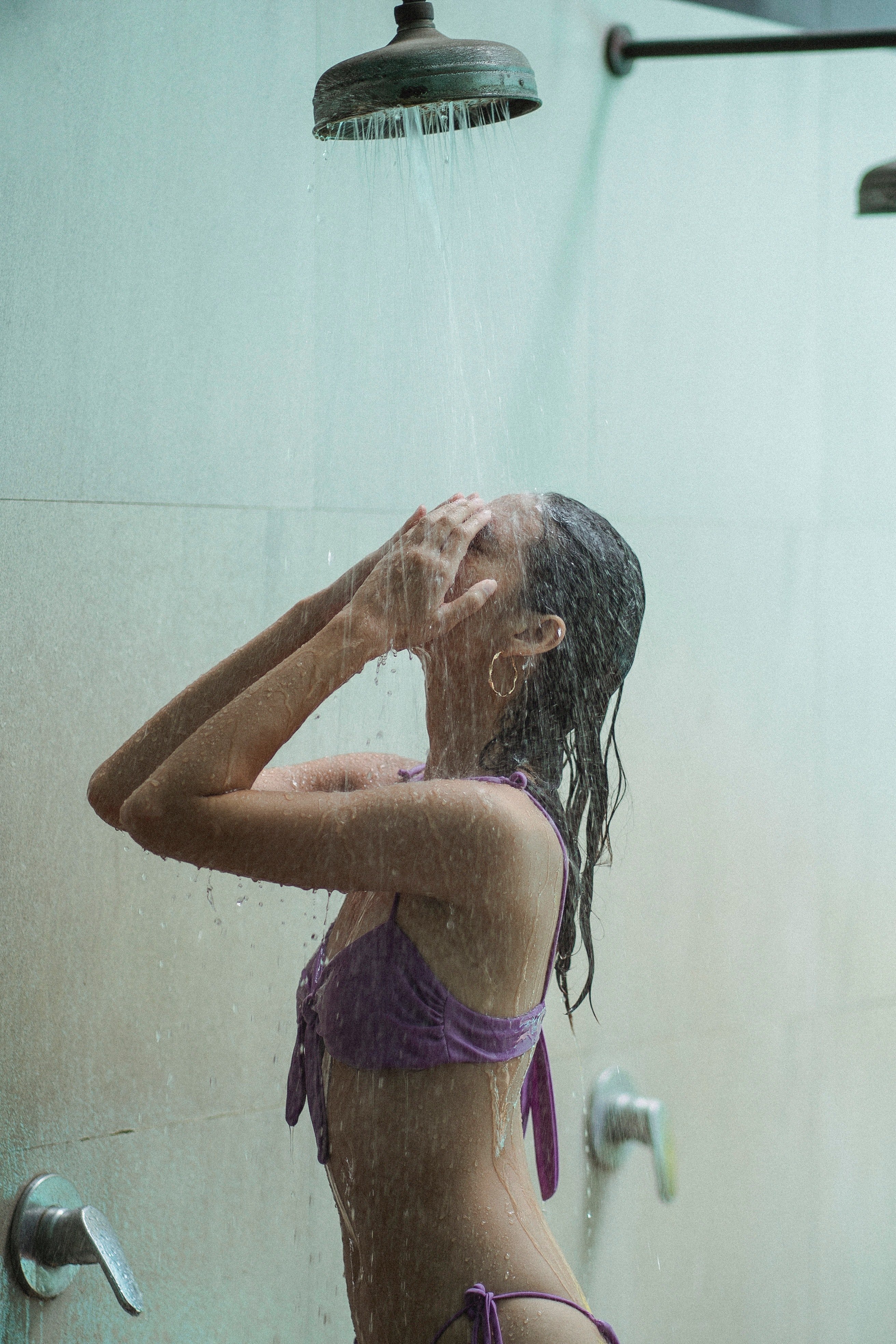 Une femme prend son bain en lavant son visage. | Photo : Pexels