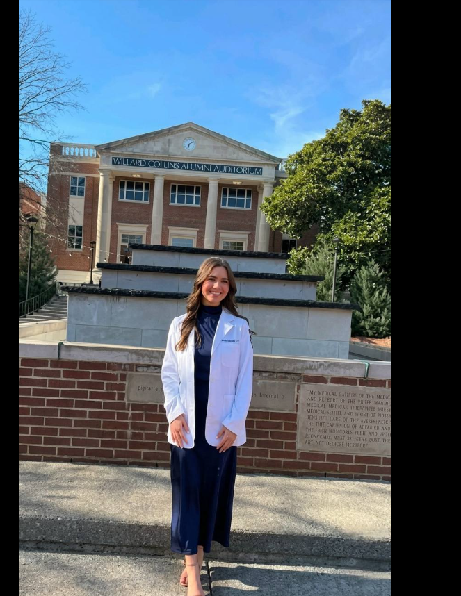 Madeline Spatafore poses in front of the Willard Collins Alumni Auditorium, wearing a white coat on campus. | Source: Facebook/Murder_and_its_victims