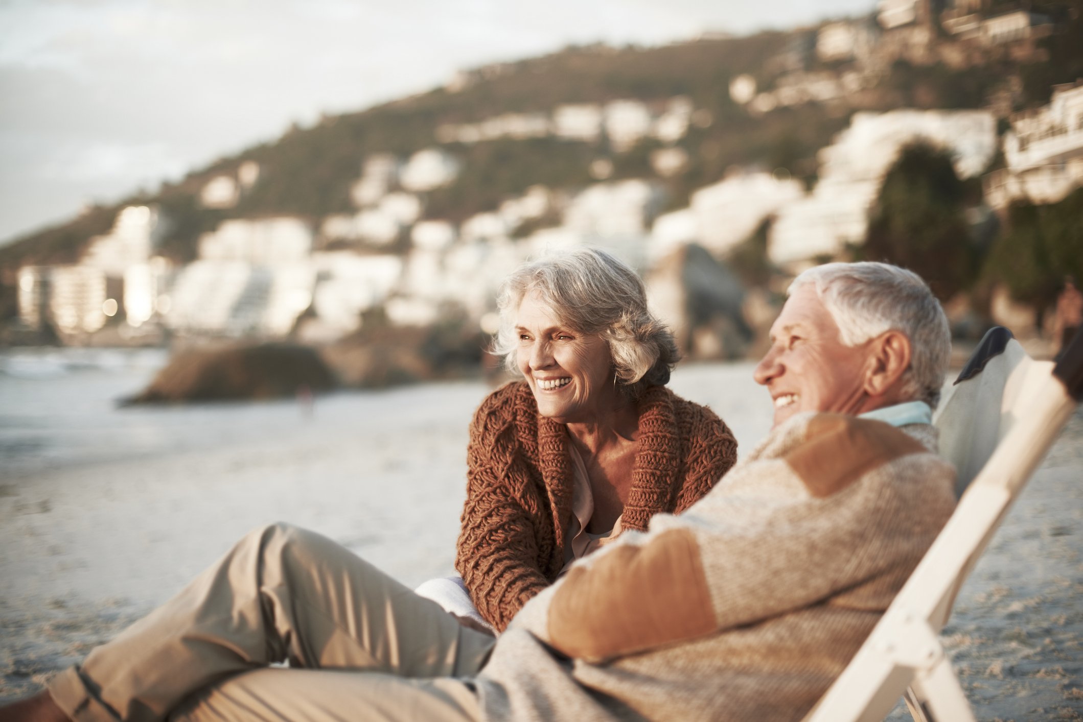 An image of a happy couple relaxing on chairs at the beach. | Photo: Getty Images