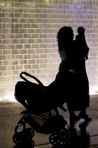 A mother and her baby standing next to a baby stroller at night. | Source: Shutterstock