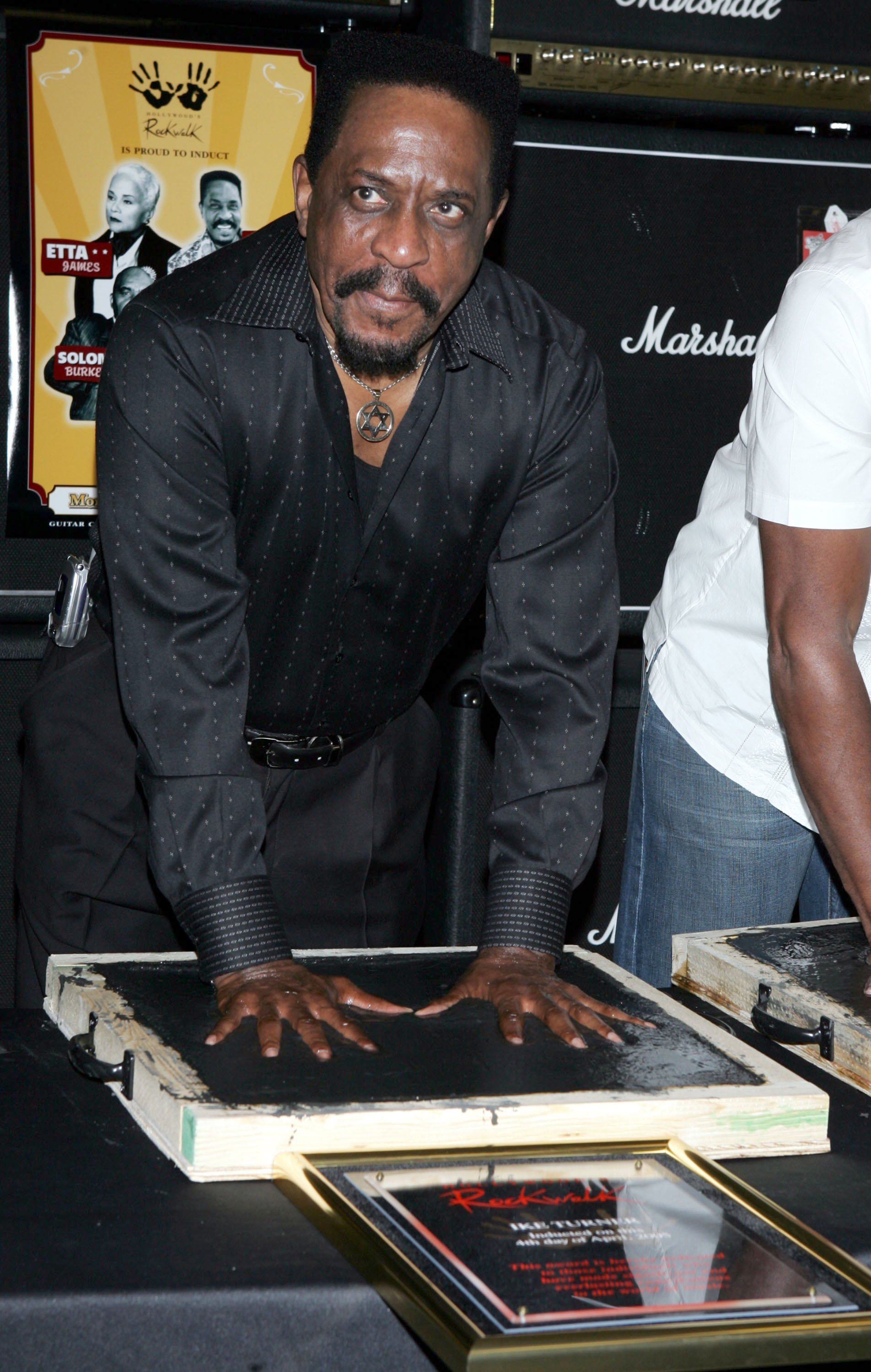  Ike Turner presses his hands into cement as he is inducted into the Hollywood Rockwalk on April 4, 2005. | Photo: GettyImages