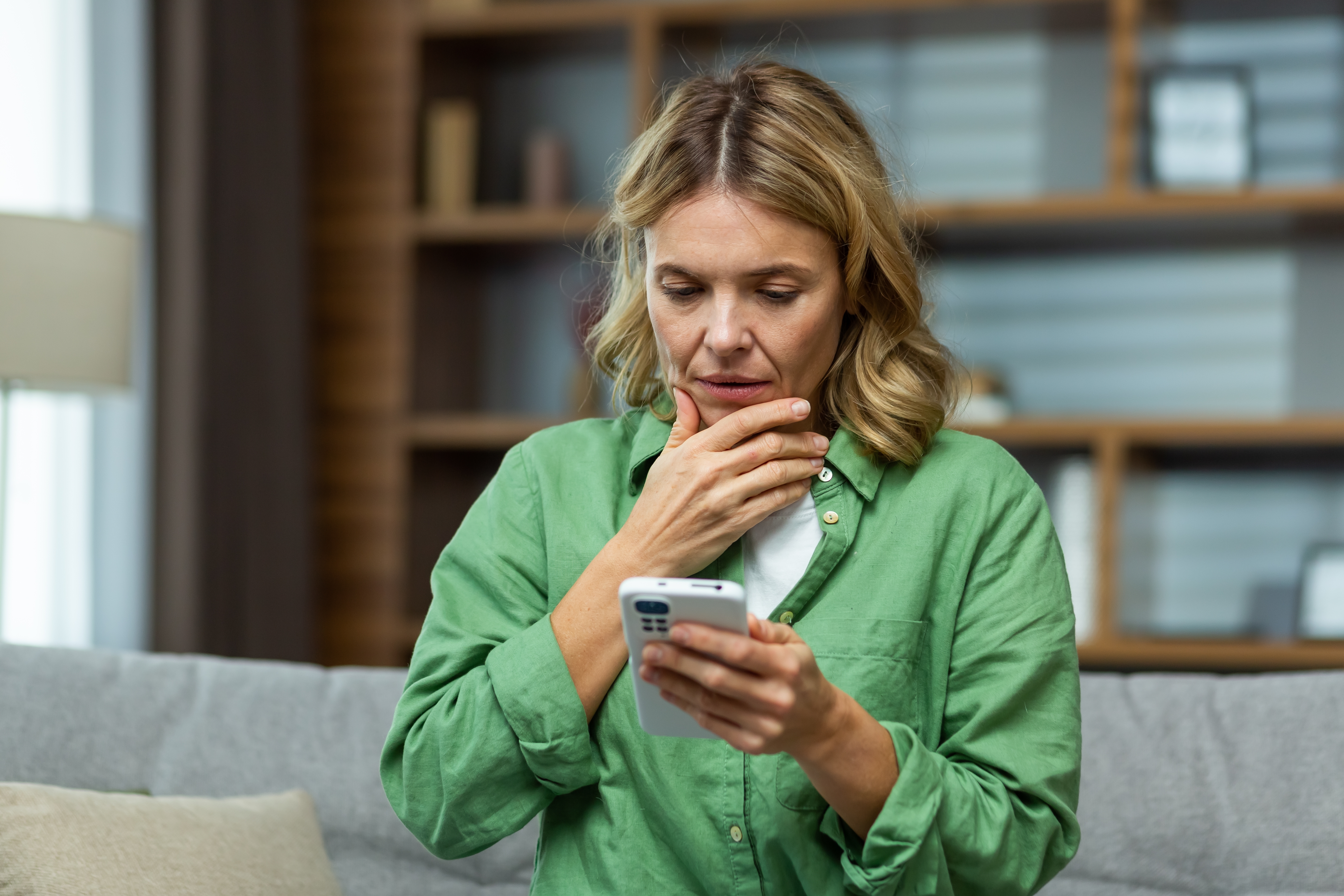 A middle-aged woman looking concerned while holding her phone | Source: Shutterstock