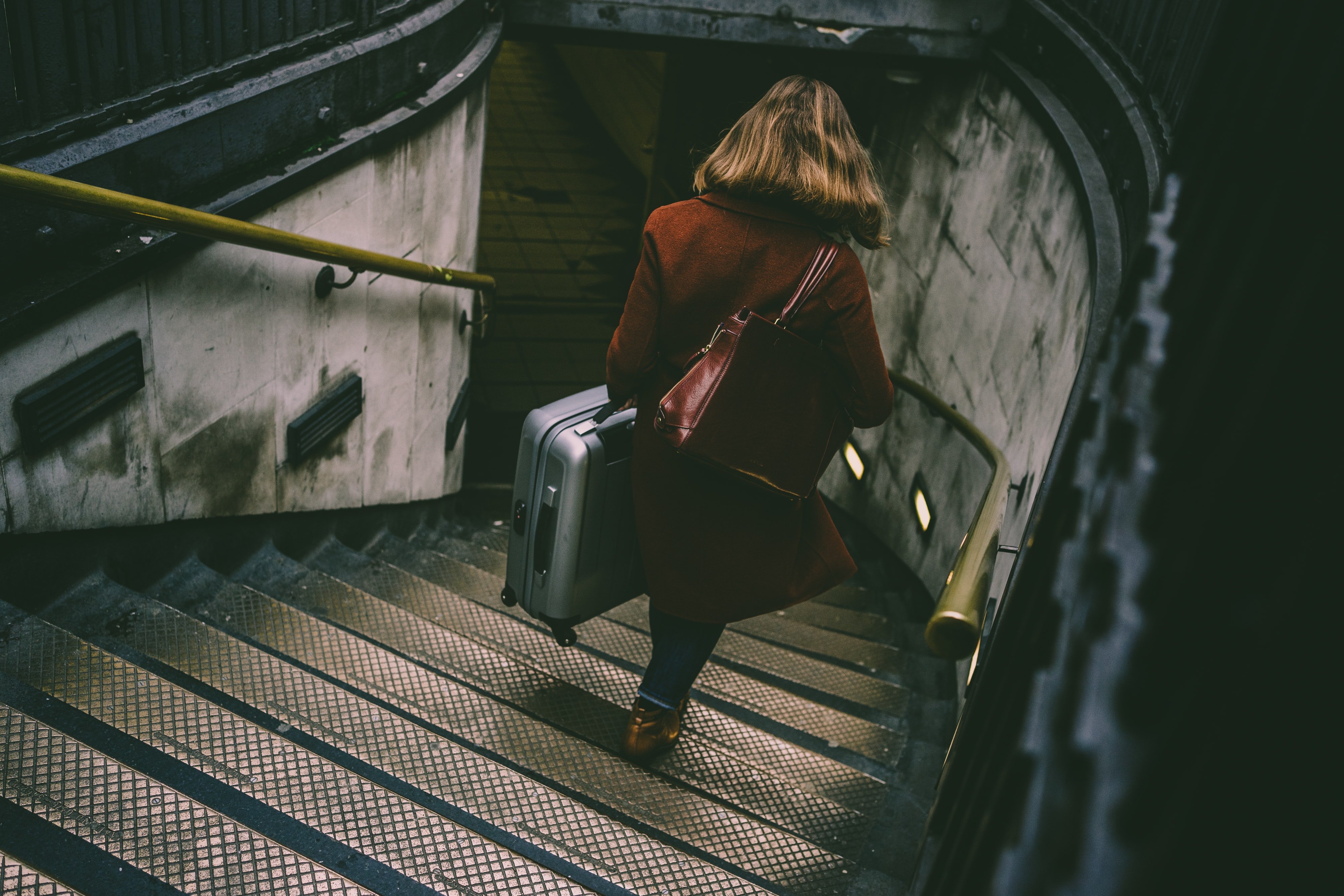 Mujer bajando unas escaleras con una maleta. | Foto: Unsplash