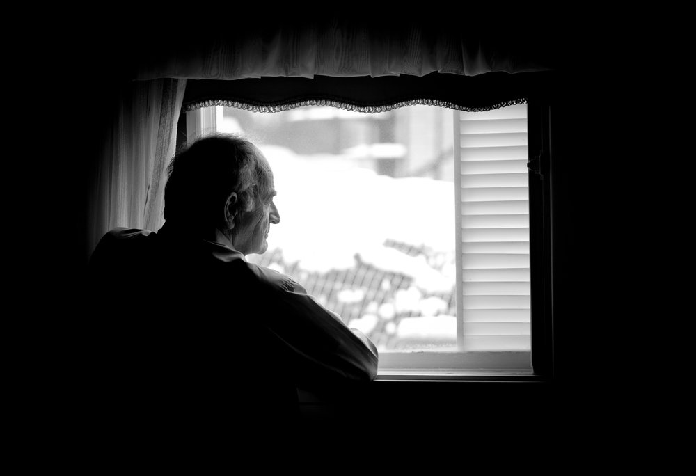 Lonely senior man looking at the window. | Photo: Shutterstock