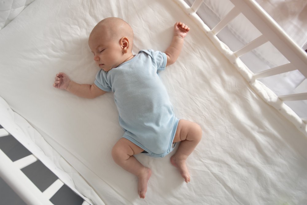 Baby liegt im Bett. | Quelle: Shutterstock