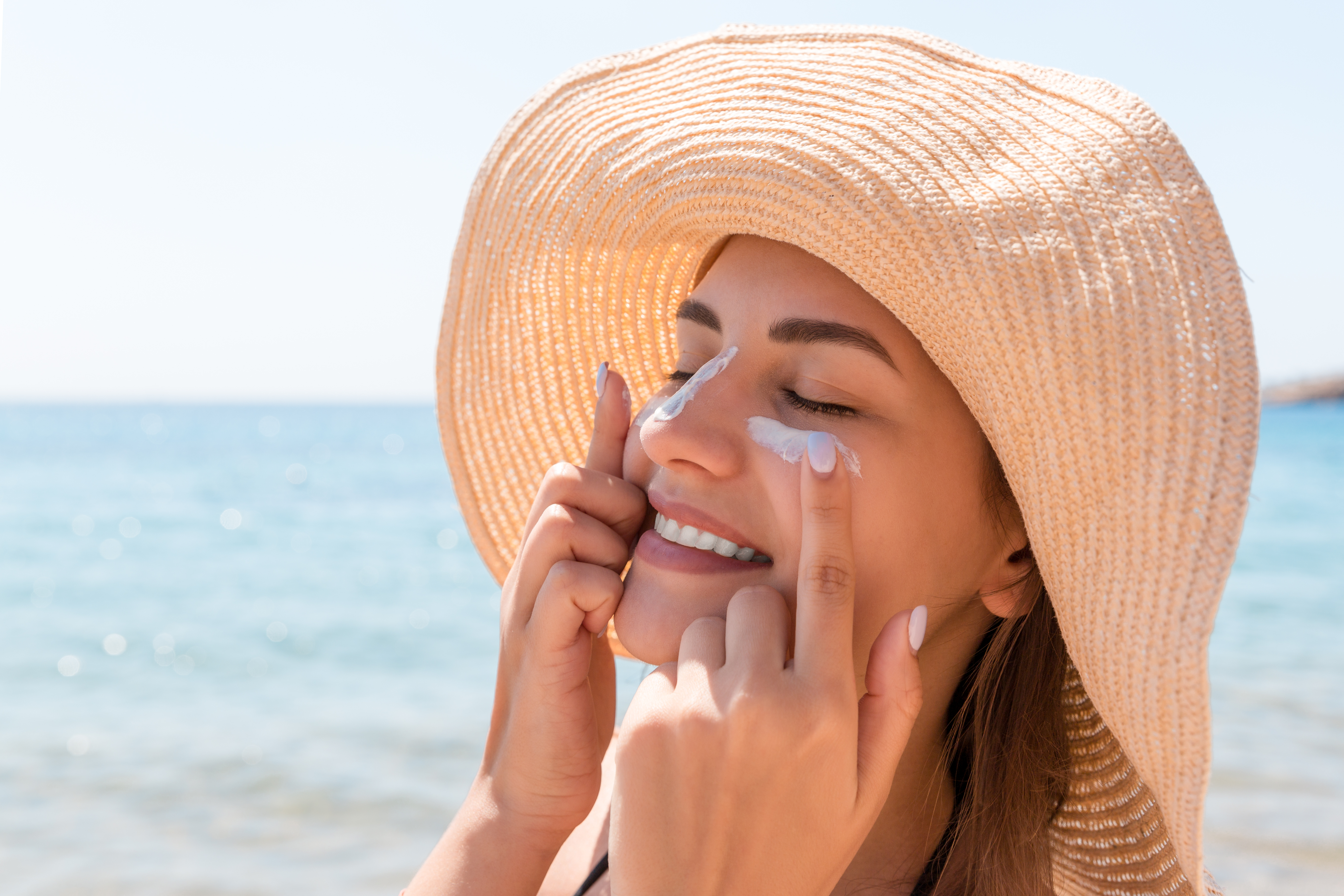 Woman applying sunscreen to her face on the beach | Source: Shutterstock