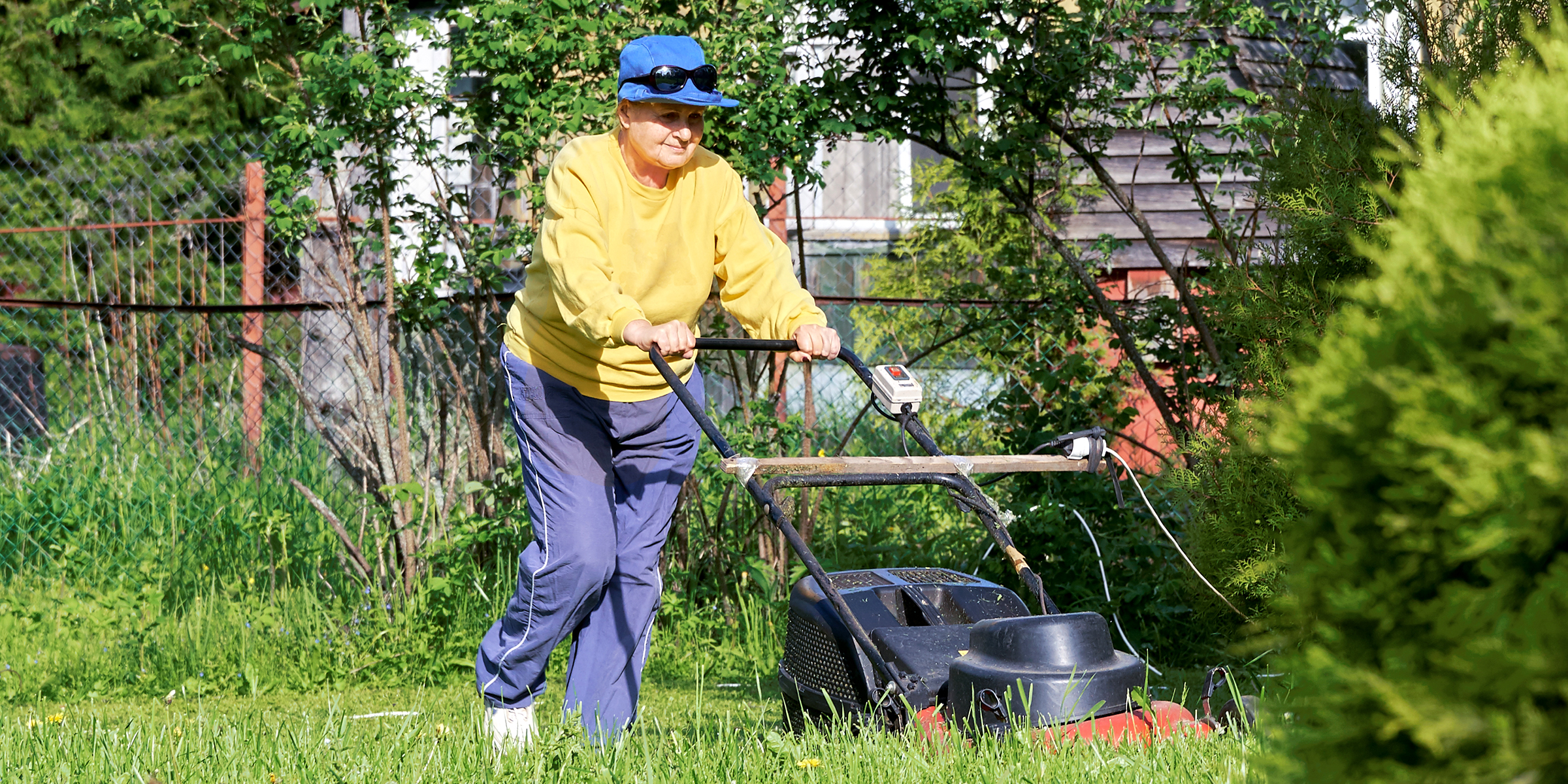 A woman mowing her lawn | Source: Shutterstock