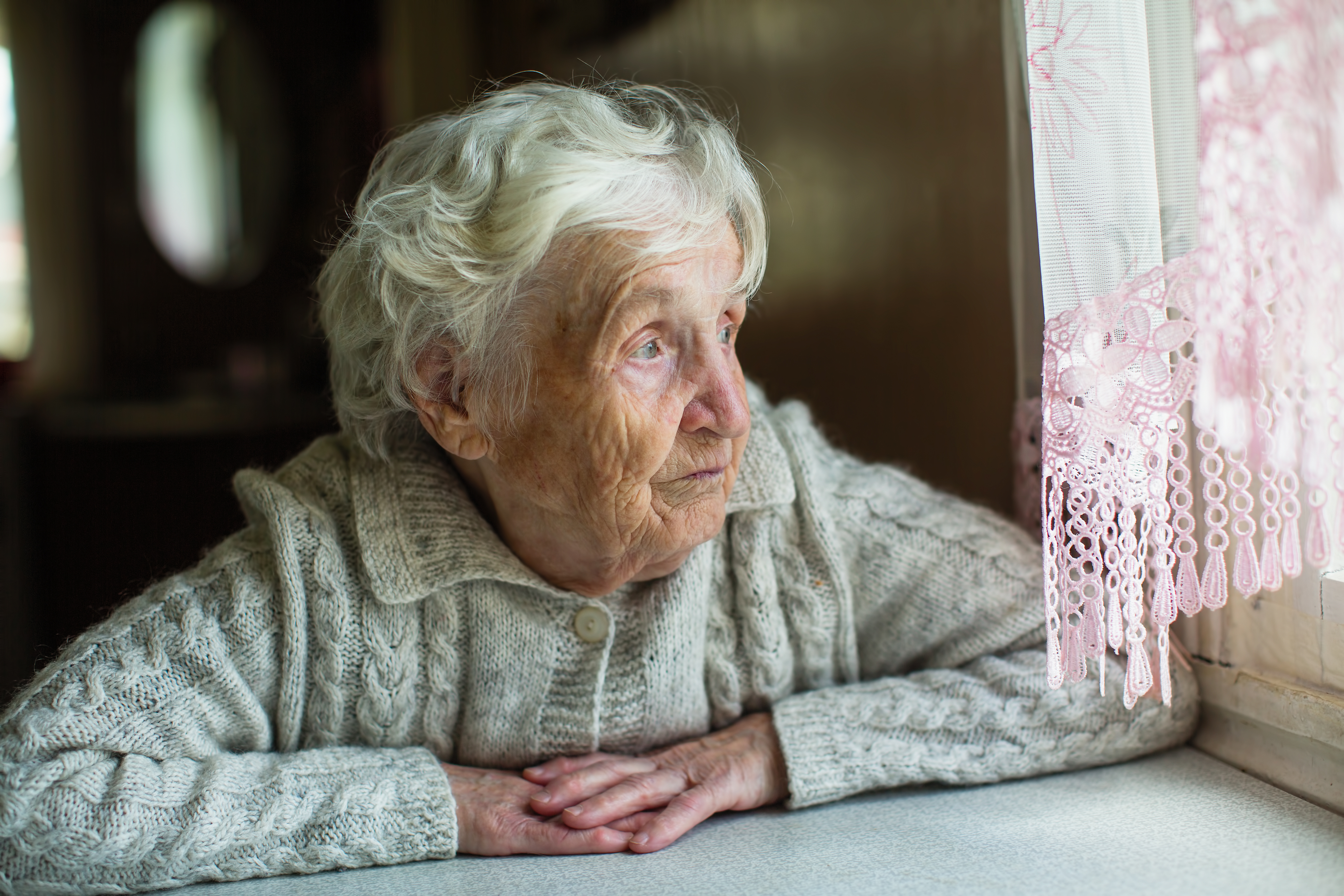 Eine ältere Frau, die aus dem Fenster schaut | Quelle: Shutterstock