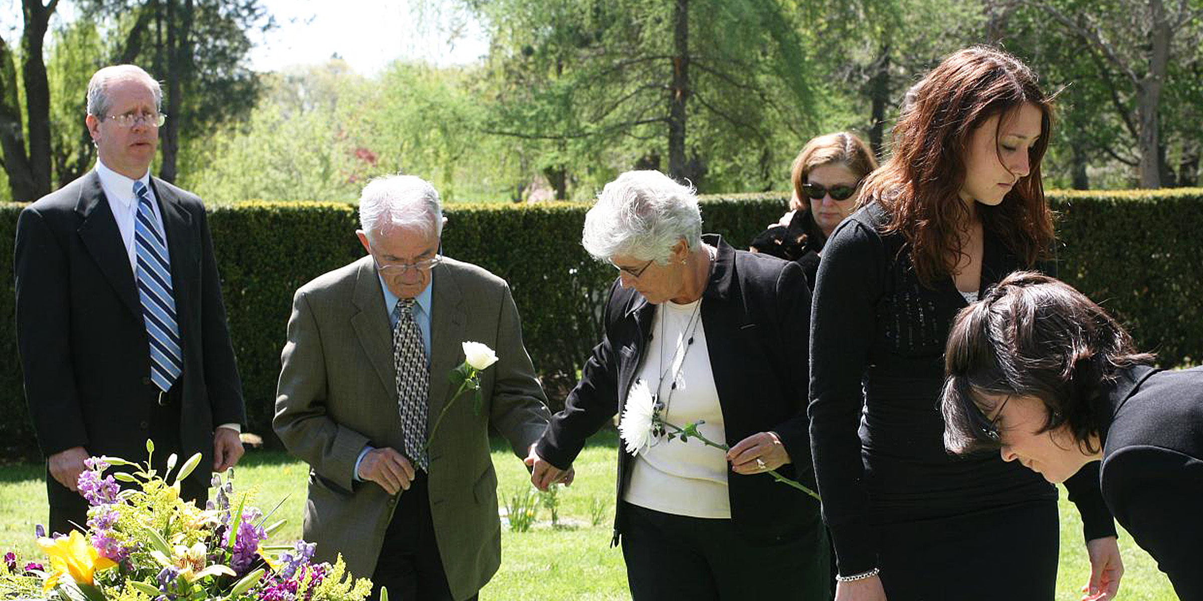 People standing near a grave | Source: Flickr