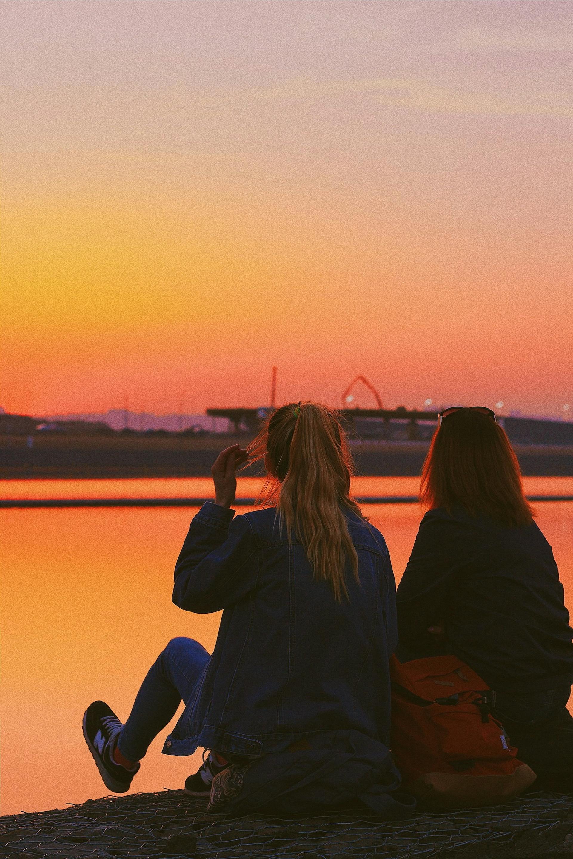 Two teenage girls sitting by a lake | Source: Pexels