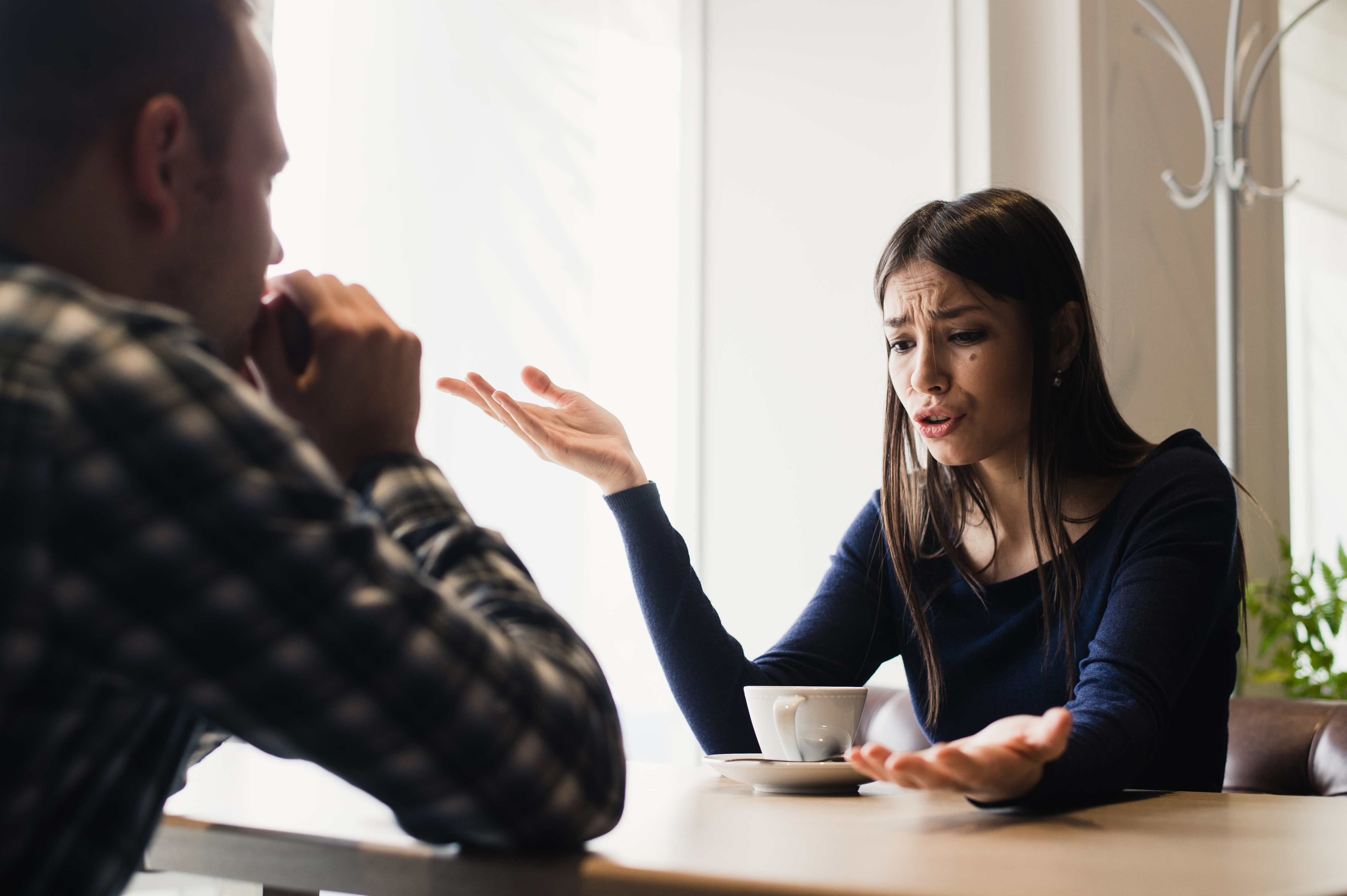 Sad woman tells a story to a youg man in cafe. | Source: Shutterstock