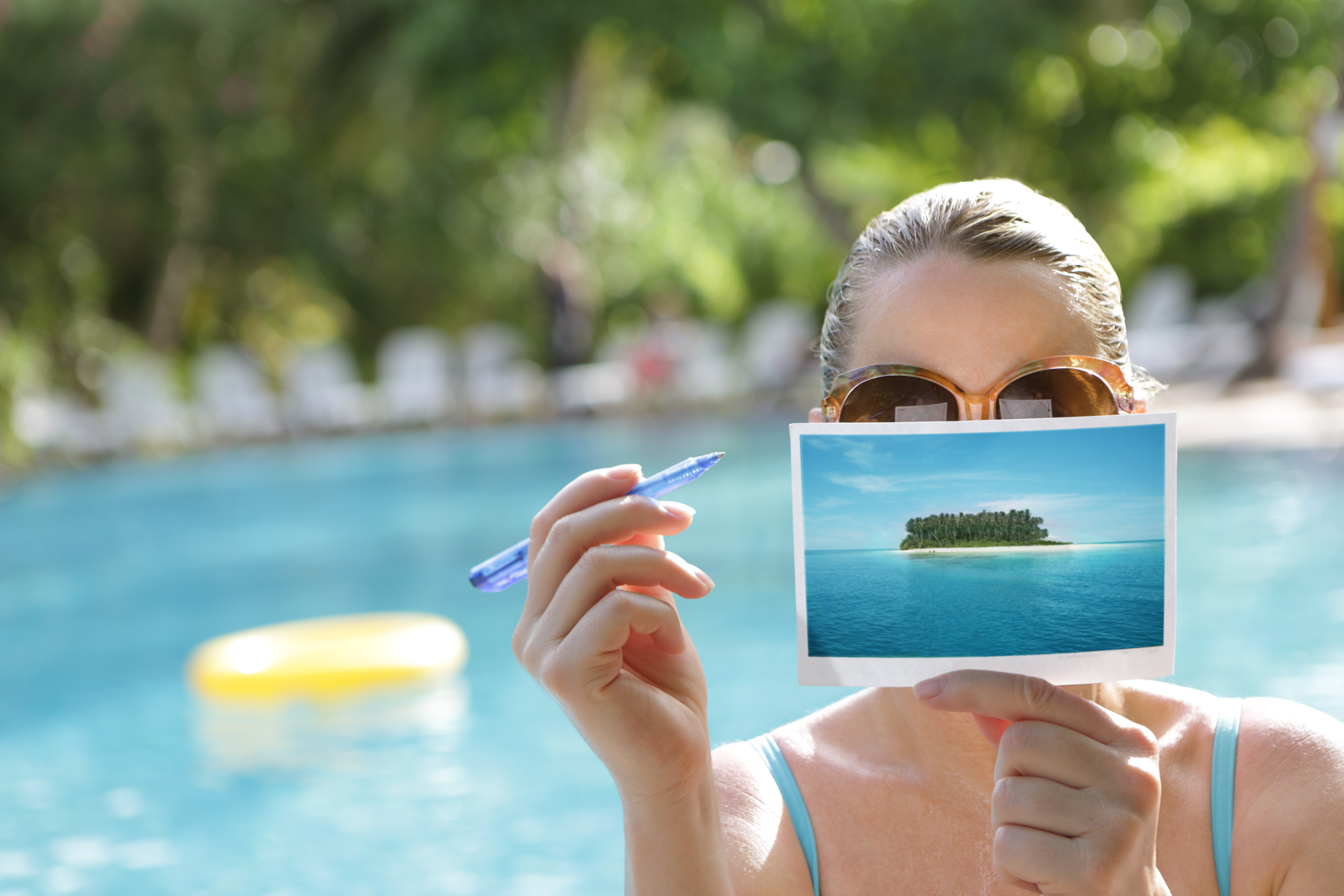 Woman writing postcard by swimming pool | Source: Getty Images