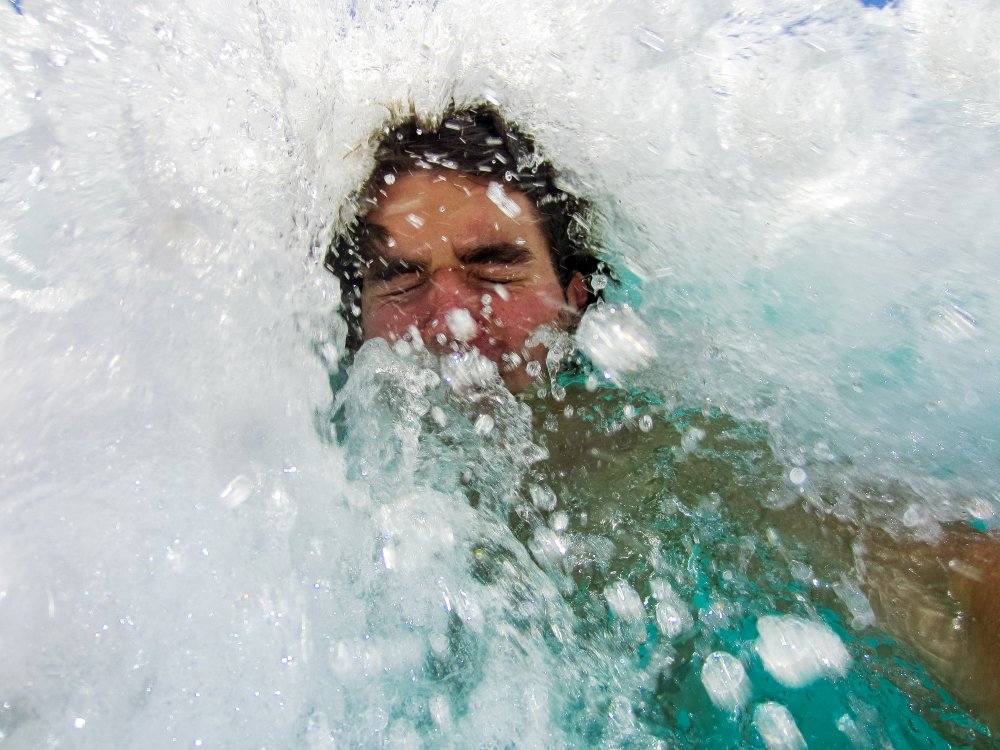 Ein Mann wird von einer Welle im Meer überrollt. I Quelle: Shutterstock