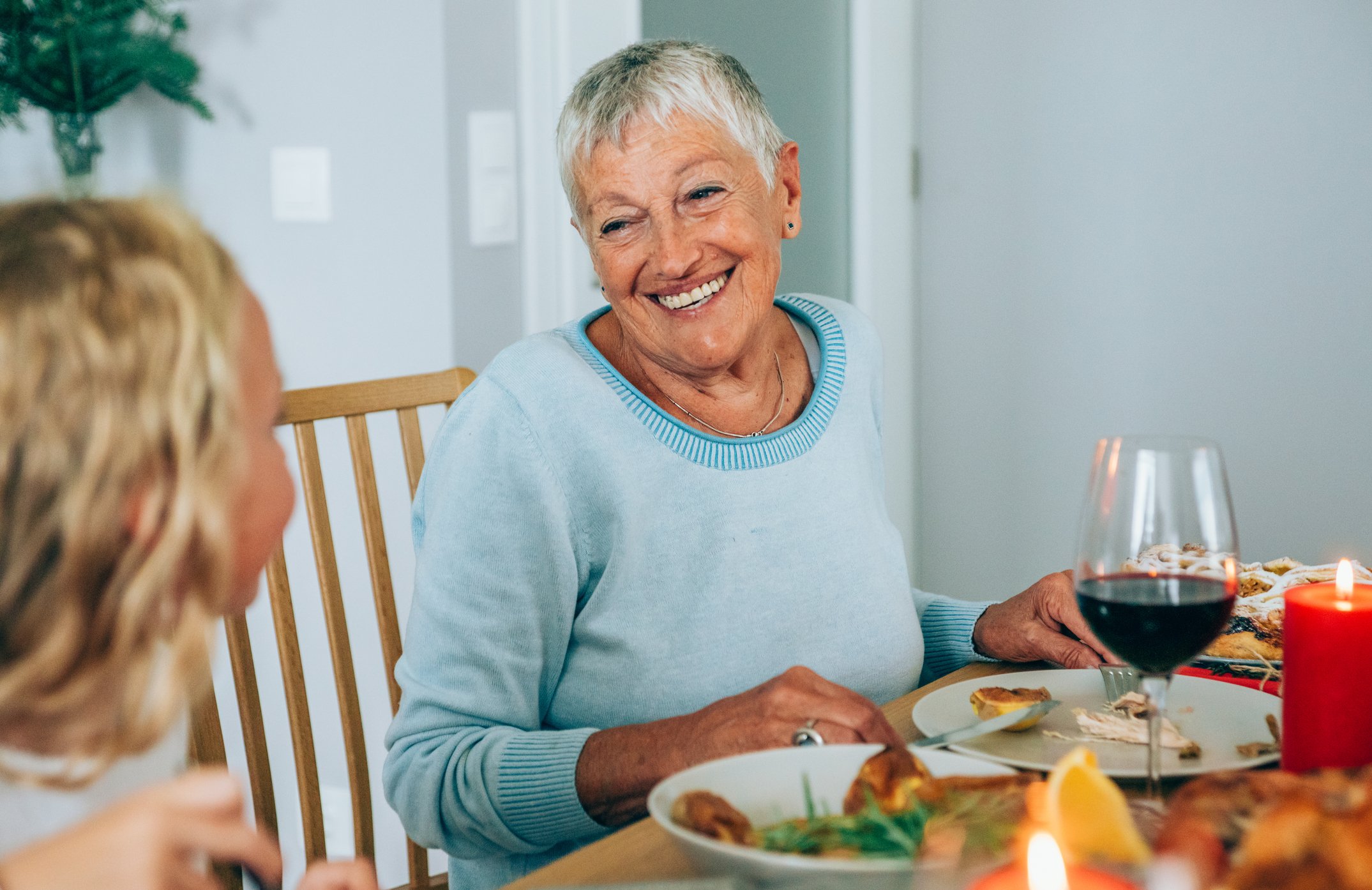 Photo of smiling senior woman during holiday dinner | Photo: Getty Images
