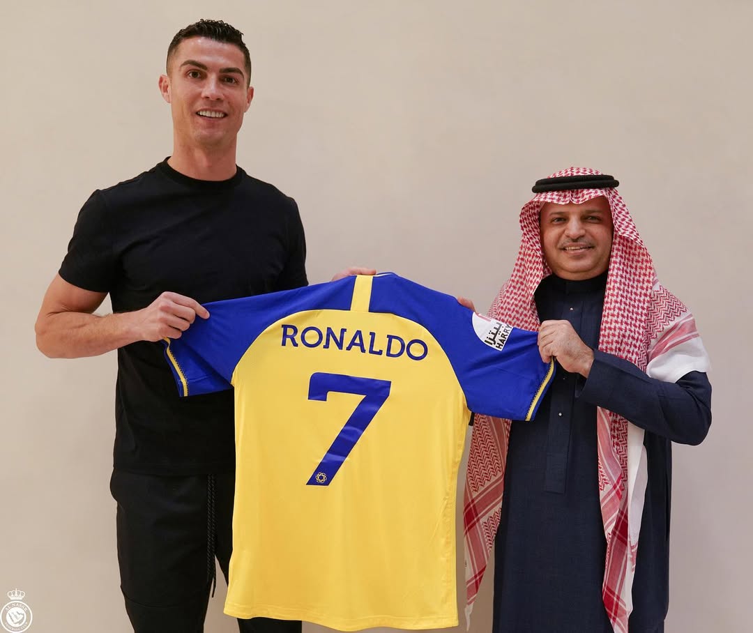 Cristiano Ronaldo posing with an official while holding a jersey, dated December 2022 | Source: Instagram/cristiano