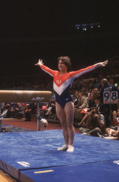  Full-length image of American gymnast Mary Lou Retton smiling while posing on the mat after her dismount from the balance beam at the Summer Olympic Games | Source: Getty Images